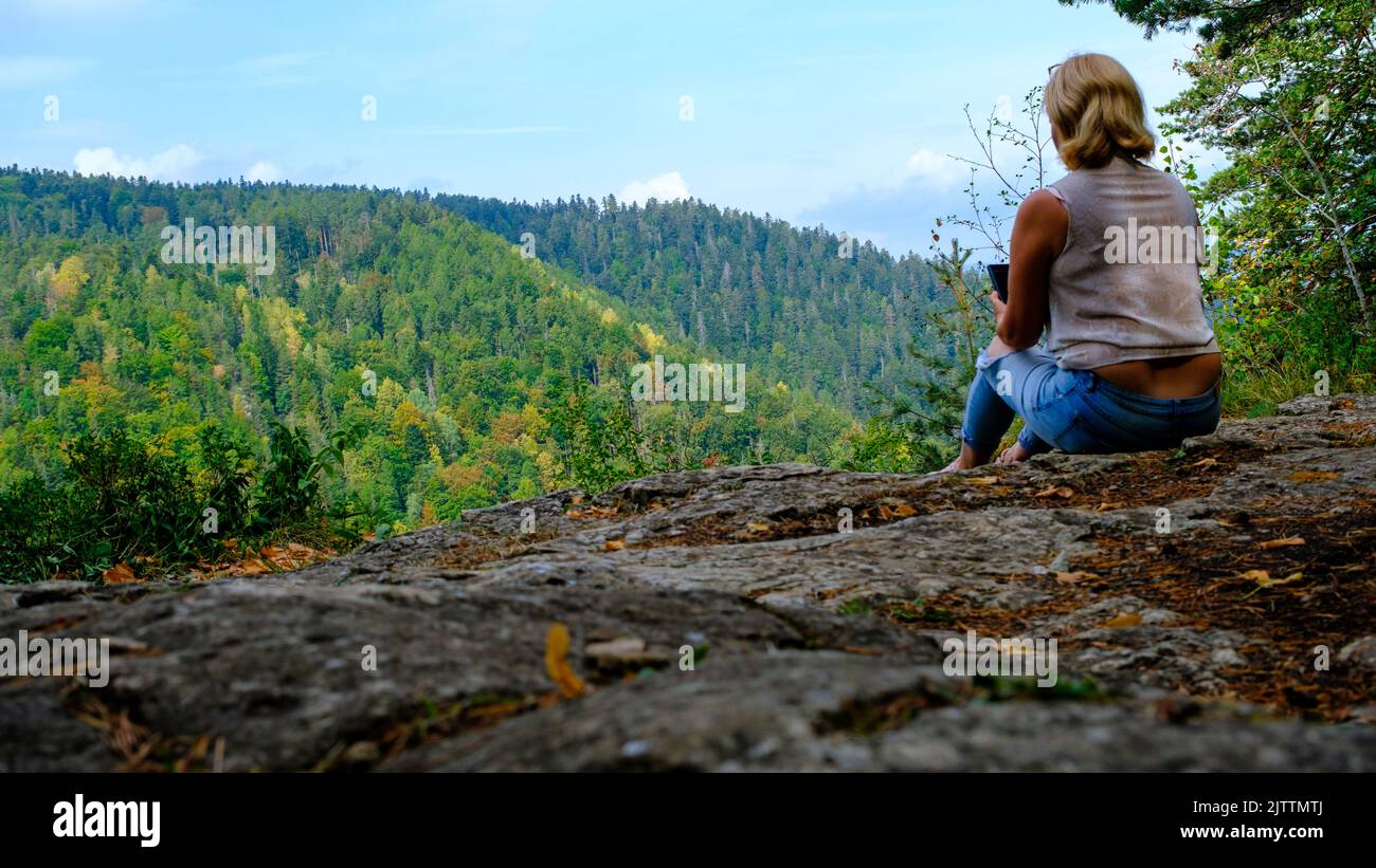 Una donna gode della vista della natura, tenendo un telefono cellulare. Una vista delle montagne più belle in una scena panoramica. Vista da Tomasovsky Vyhlad in Foto Stock