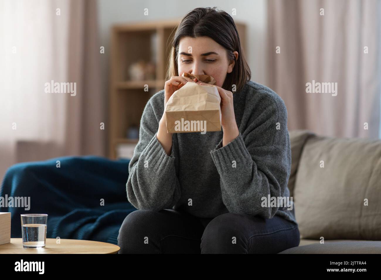 donna con attacco di panico che respira al sacco a casa Foto Stock