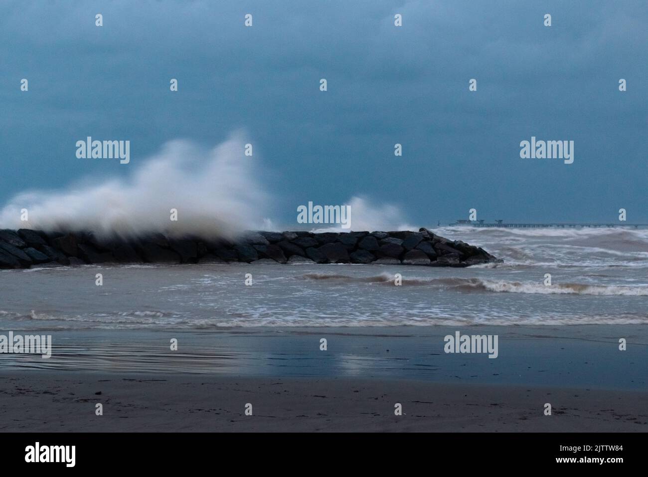 Grandi onde si schiantano contro la frangiflutti della spiaggia di El Puerto de Sagunto in una giornata tempestosa sotto un cielo drammatico. Porto di Sagunt - Valencia Foto Stock