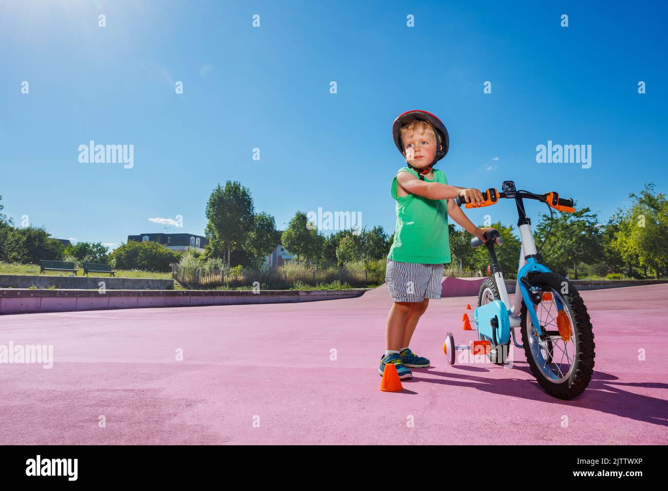 Il ragazzino si trova in piedi con la bicicletta al parco a rotelle della città Foto Stock