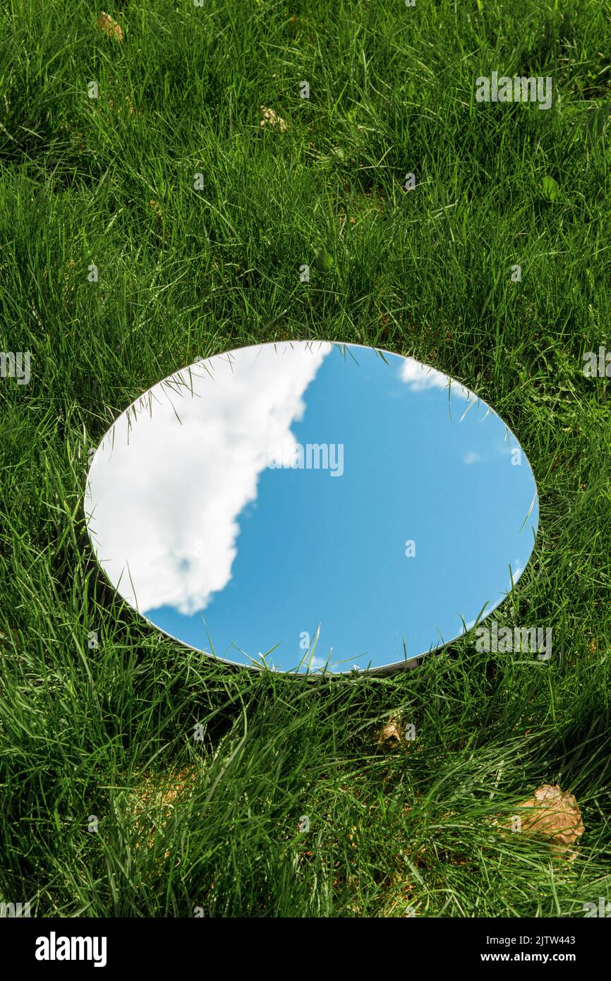 cielo e nuvola riflesso in specchio rotondo su erba Foto Stock