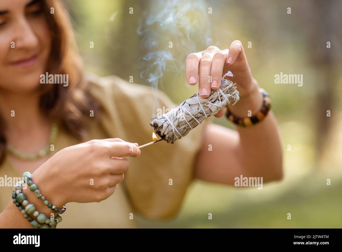 donna con salvia che esegue rituale magico nella foresta Foto Stock