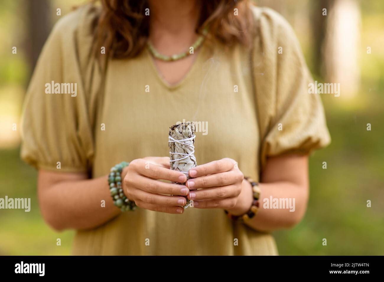 donna con salvia che esegue rituale magico nella foresta Foto Stock