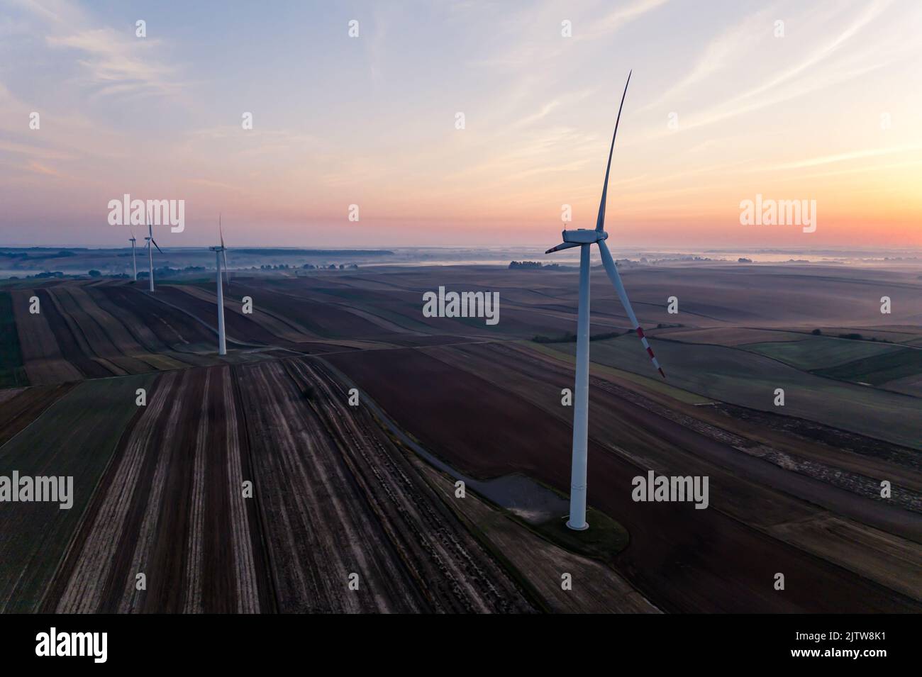 Turbine eoliche in piedi in campi colorati all'alba. Orizzonte nebbia. Energia rinnovabile. Ecologia. Scatto orizzontale . Foto di alta qualità Foto Stock