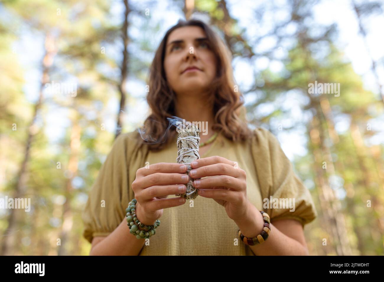 donna con salvia che esegue rituale magico nella foresta Foto Stock