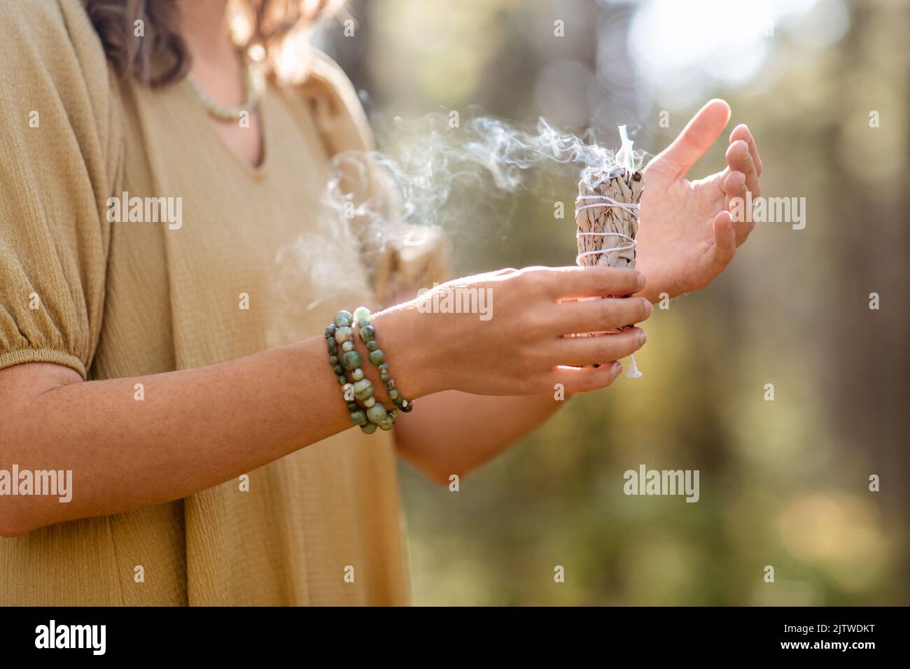 donna con salvia che esegue rituale magico nella foresta Foto Stock