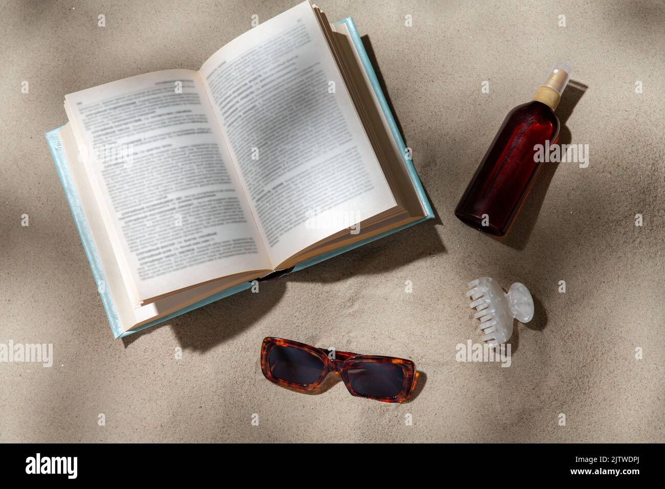 prenota, occhiali da sole e crema solare sulla spiaggia Foto Stock
