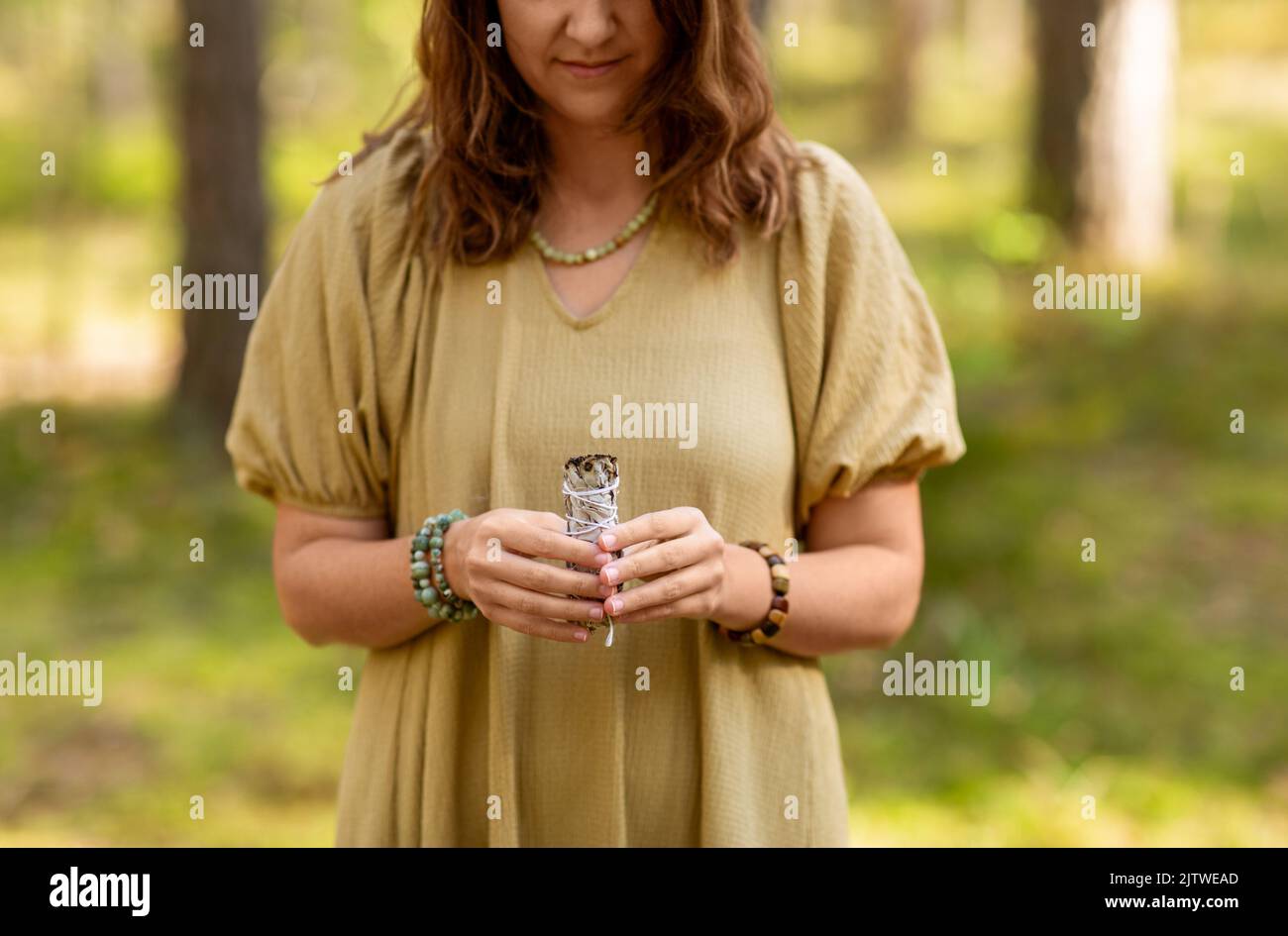 donna con salvia che esegue rituale magico nella foresta Foto Stock