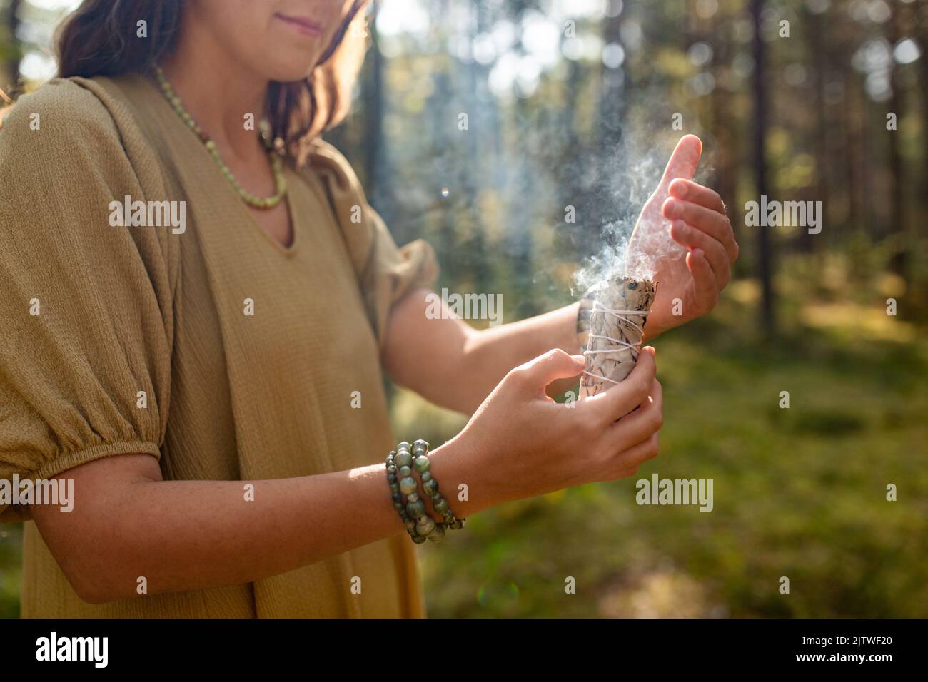 donna con salvia che esegue rituale magico nella foresta Foto Stock