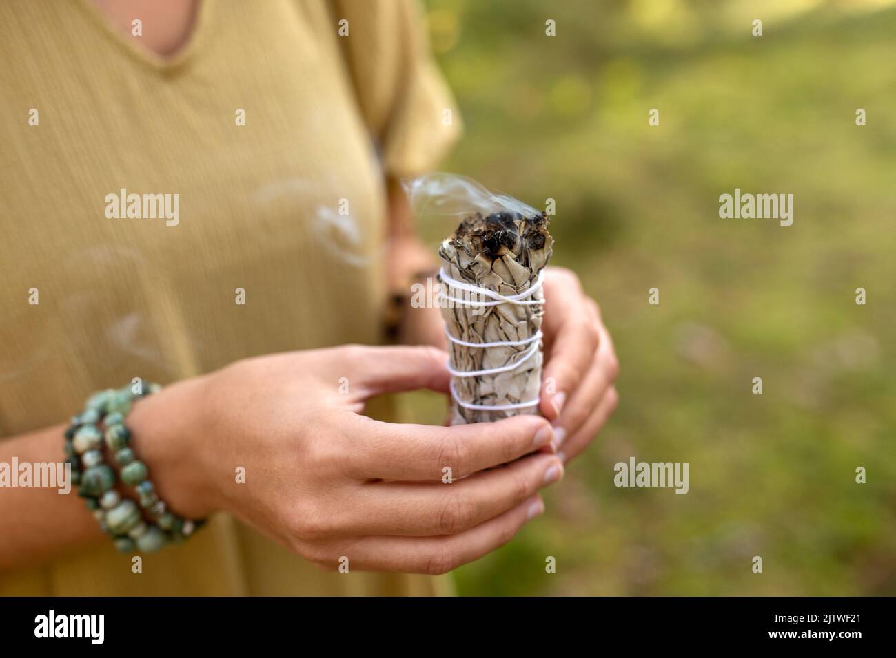 donna con salvia che esegue rituale magico nella foresta Foto Stock