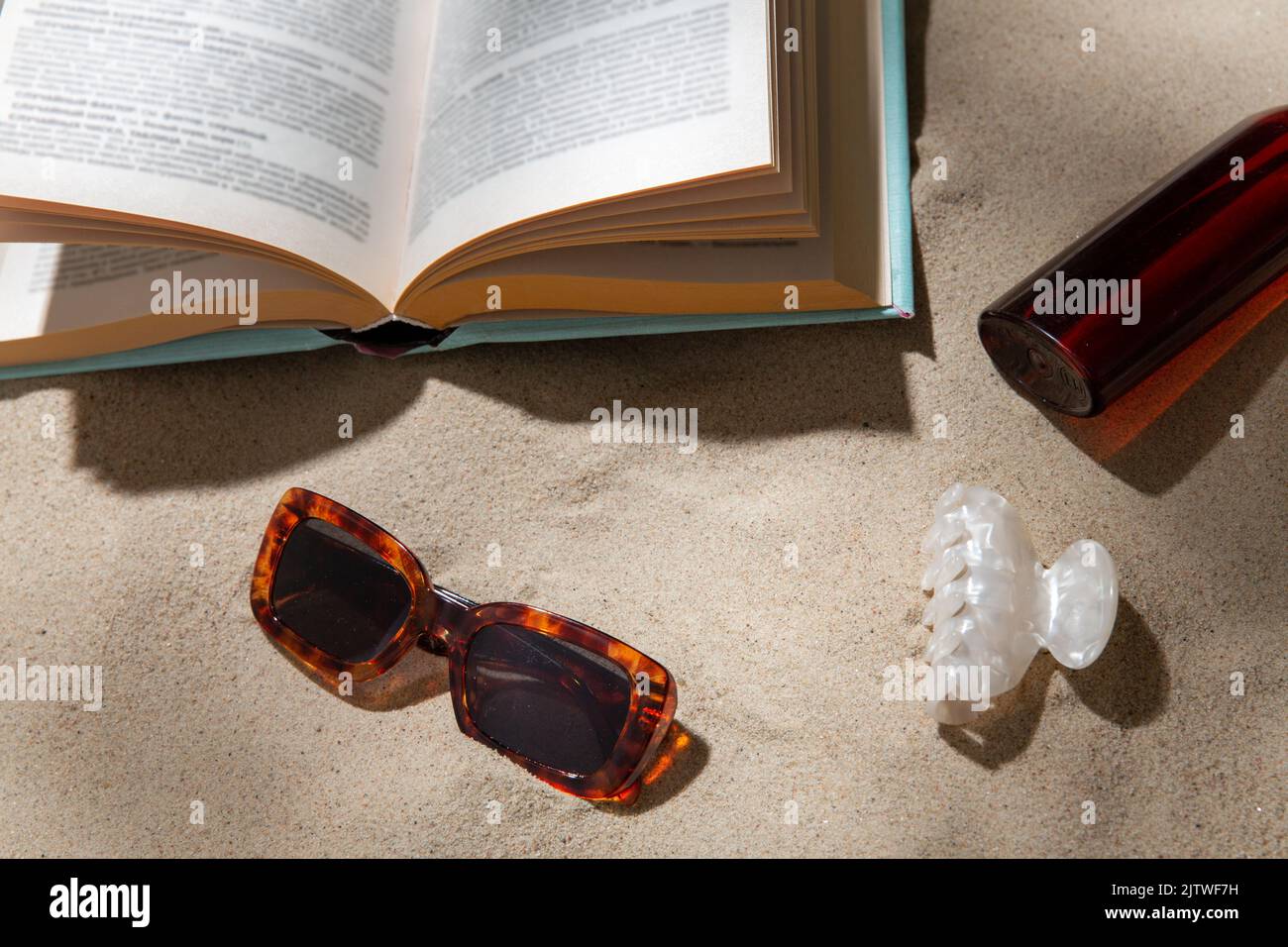 prenota, occhiali da sole e crema solare sulla spiaggia Foto Stock