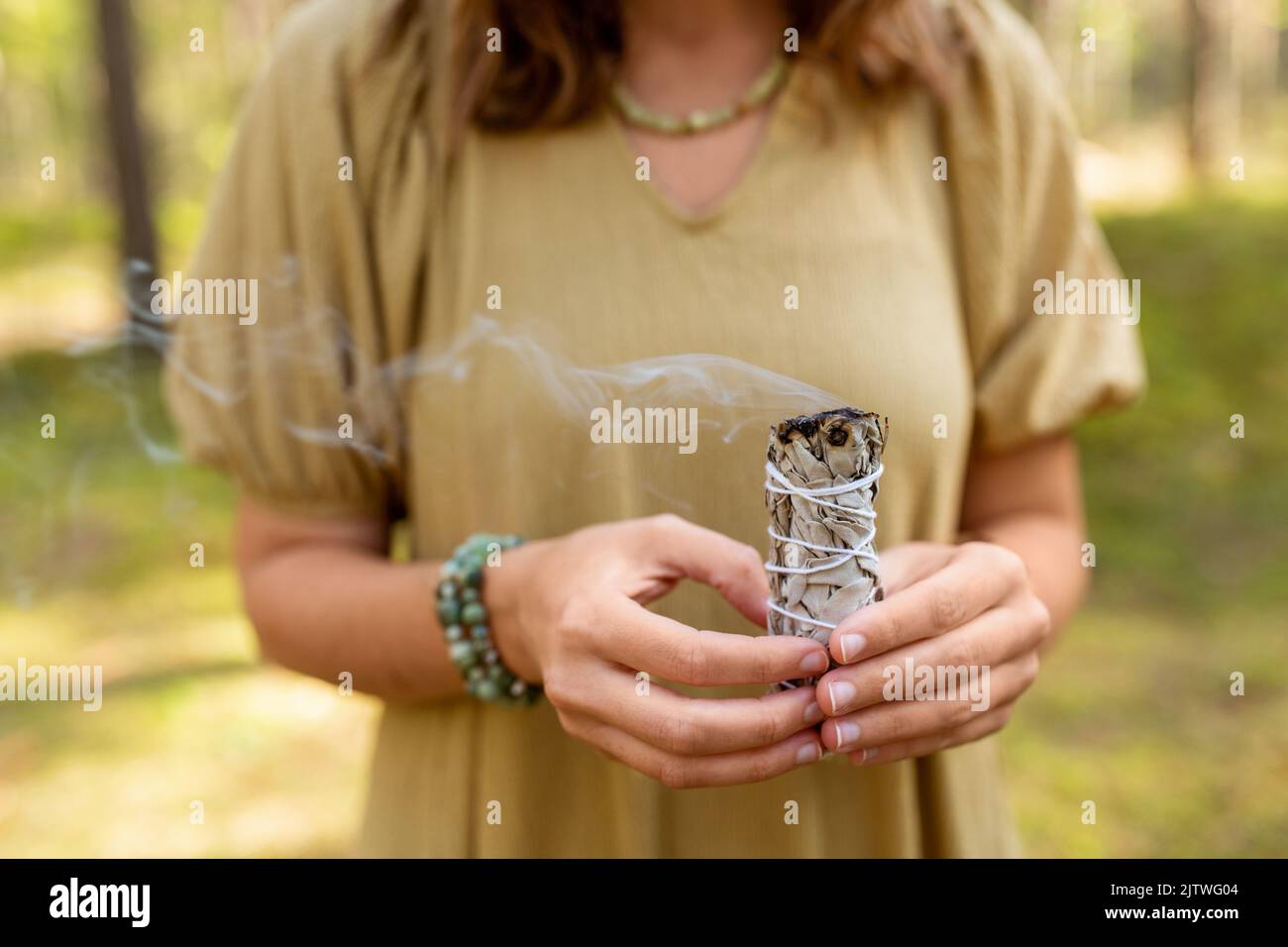 donna con salvia che esegue rituale magico nella foresta Foto Stock