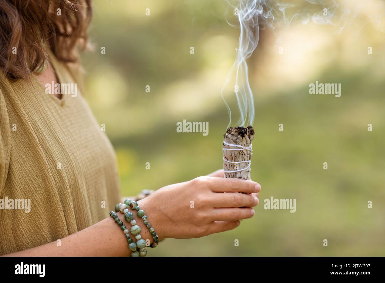 donna con salvia che esegue rituale magico nella foresta Foto Stock