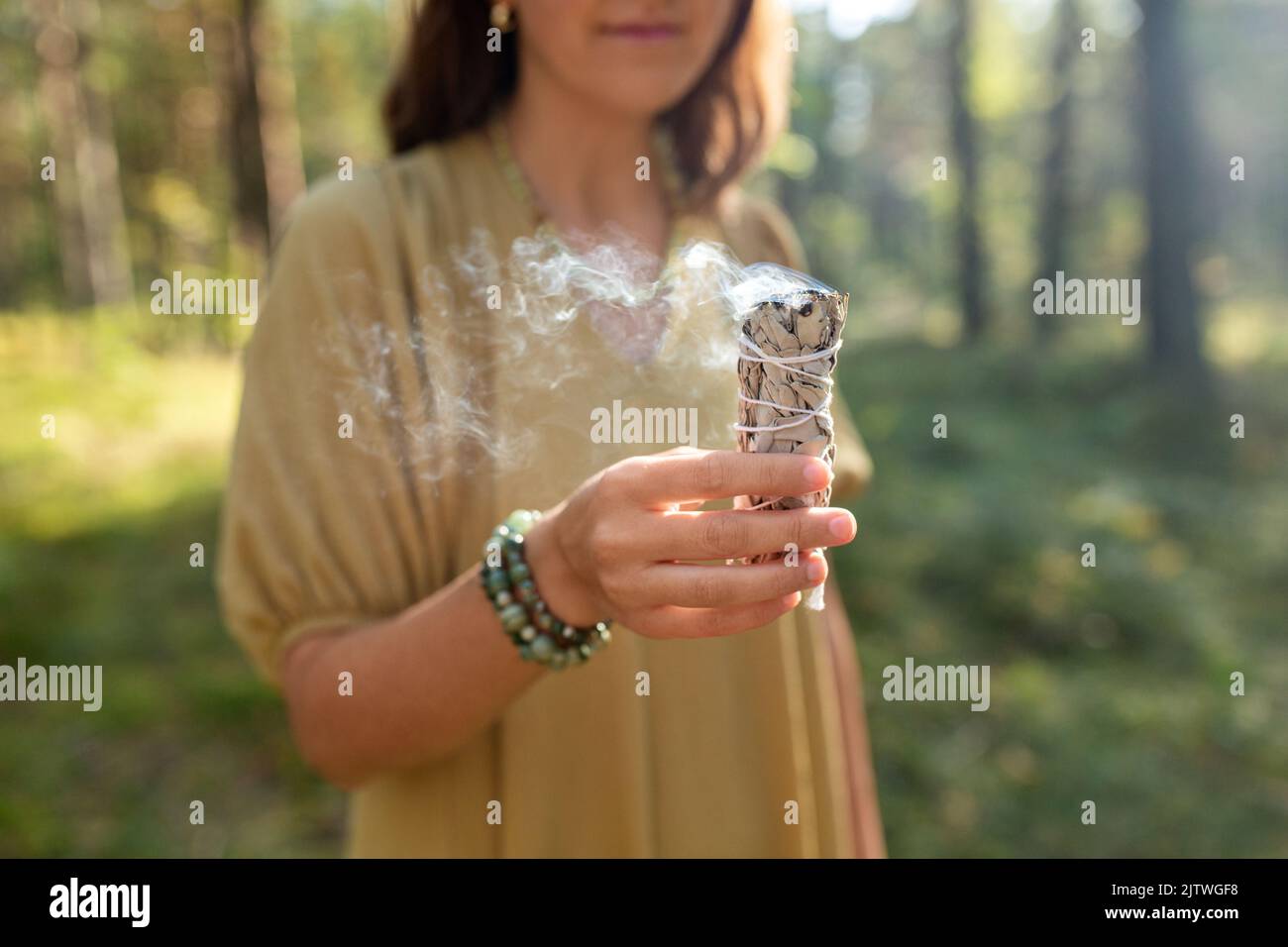 donna con salvia che esegue rituale magico nella foresta Foto Stock