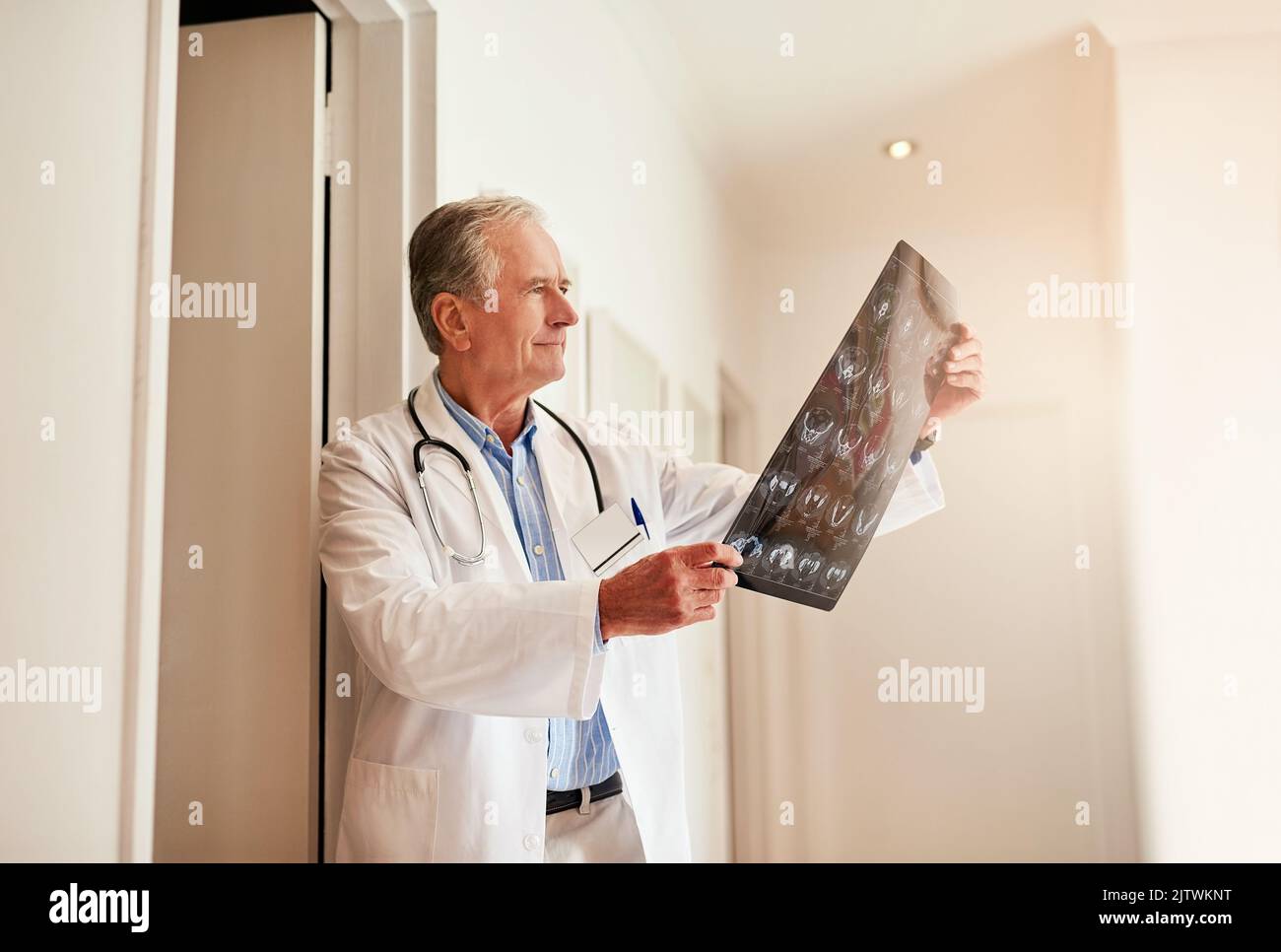 Sì, questo conferma ciò che ho pensato: Un medico maturo che tiene in mano una radiografia per esaminarla. Foto Stock