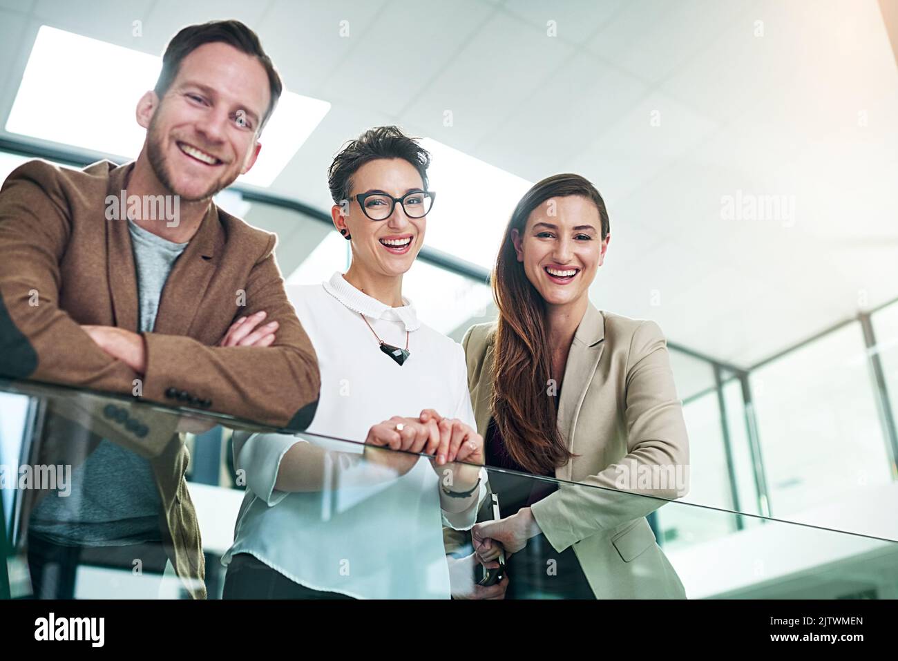 I getters di go dell'azienda. Ritratto di un gruppo di colleghi appoggiati su una ringhiera in un grande ufficio moderno. Foto Stock