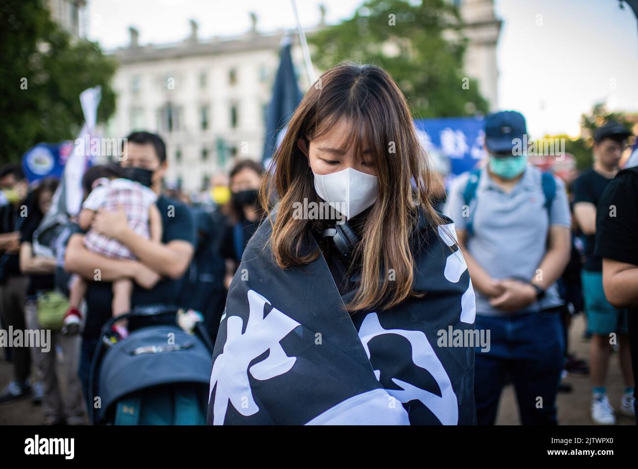 Londra, Regno Unito. 31st ago, 2022. Una donna avvolta in uno striscione di protesta di Hong Kong si inchina la testa durante un minuto di silenzio nel Parliament Square Garden. I manifestanti si sono riuniti a Londra il terzo anniversario della presenza della polizia di Hong Kong in una stazione della metropolitana e hanno picchiato i manifestanti e i pendolari, un evento che secondo gli attivisti pro-democrazia esemplifica l'impunità e gli abusi della polizia di Hong Kong. Credit: SOPA Images Limited/Alamy Live News Foto Stock