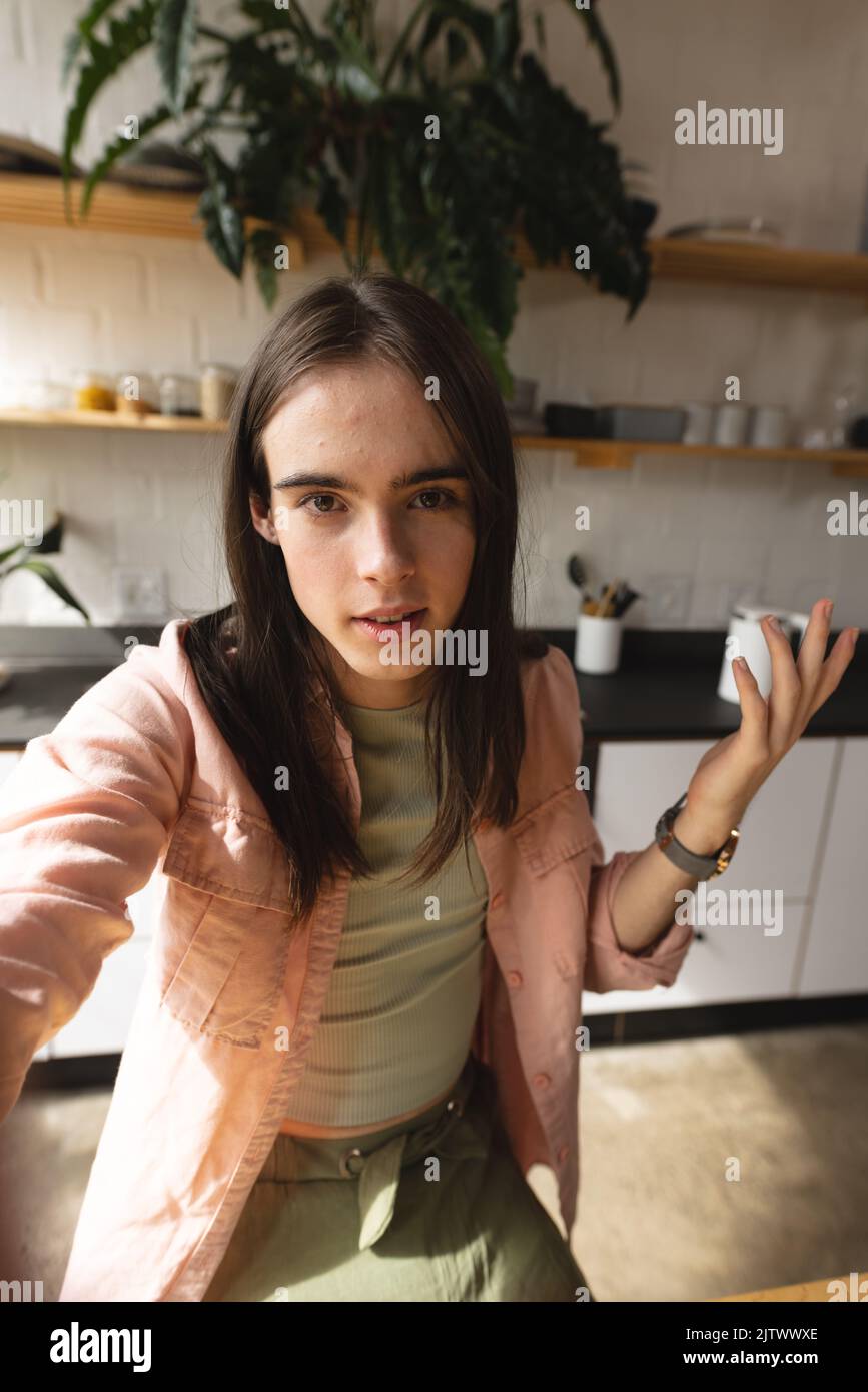 Ritratto di donna trans non binary guardando la macchina fotografica in cucina a casa Foto Stock