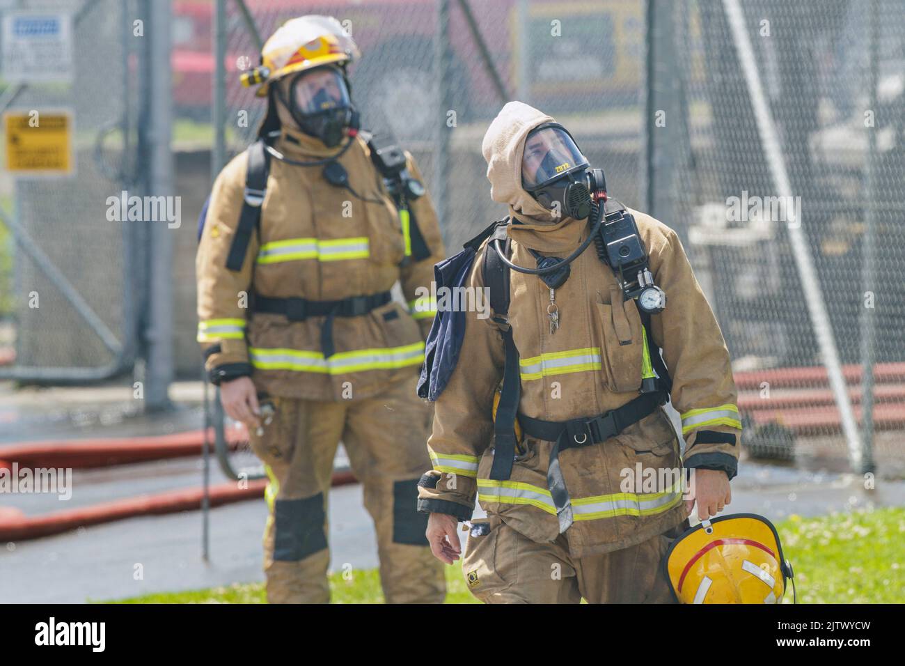 Due respiratori che indossano un pompiere guardano un edificio in fiamme Foto Stock
