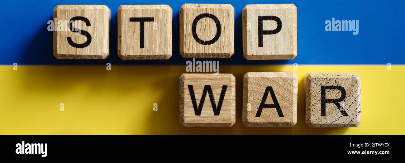 Stop guerra scritto su cubi di legno sullo sfondo della bandiera ucraino primo piano Foto Stock
