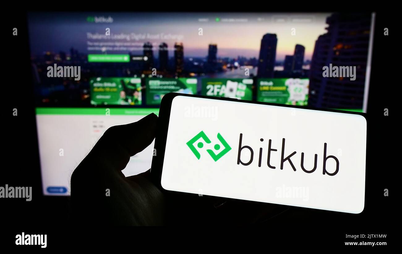 Persona che tiene il cellulare con il logo della società thailandese criptato Bitkub Online Co. Ltd. Sullo schermo di fronte al sito web aziendale. Messa a fuoco sul display del telefono. Foto Stock