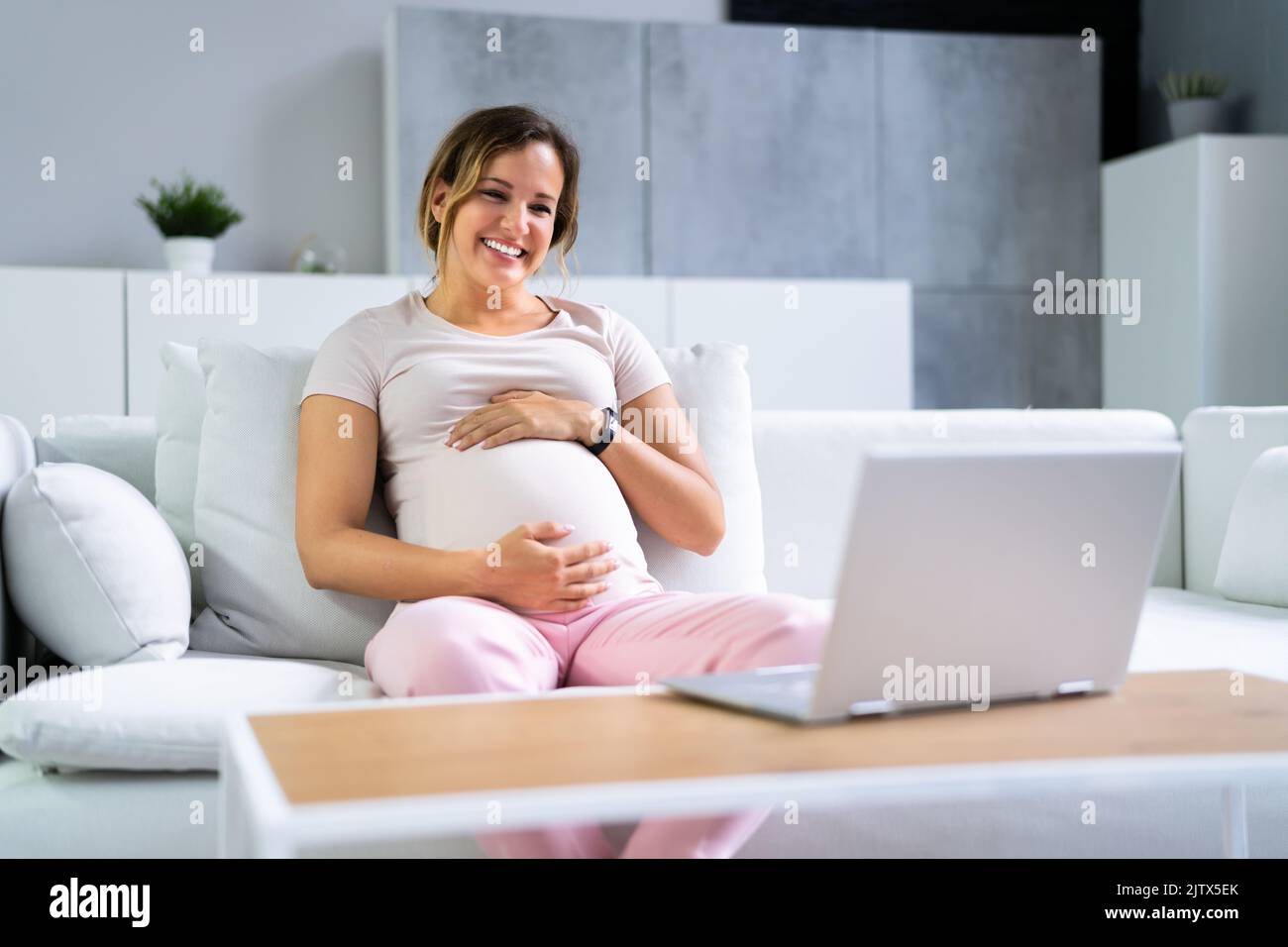 Donna incinta che usa la videochiamata in linea con medico sul laptop Foto Stock