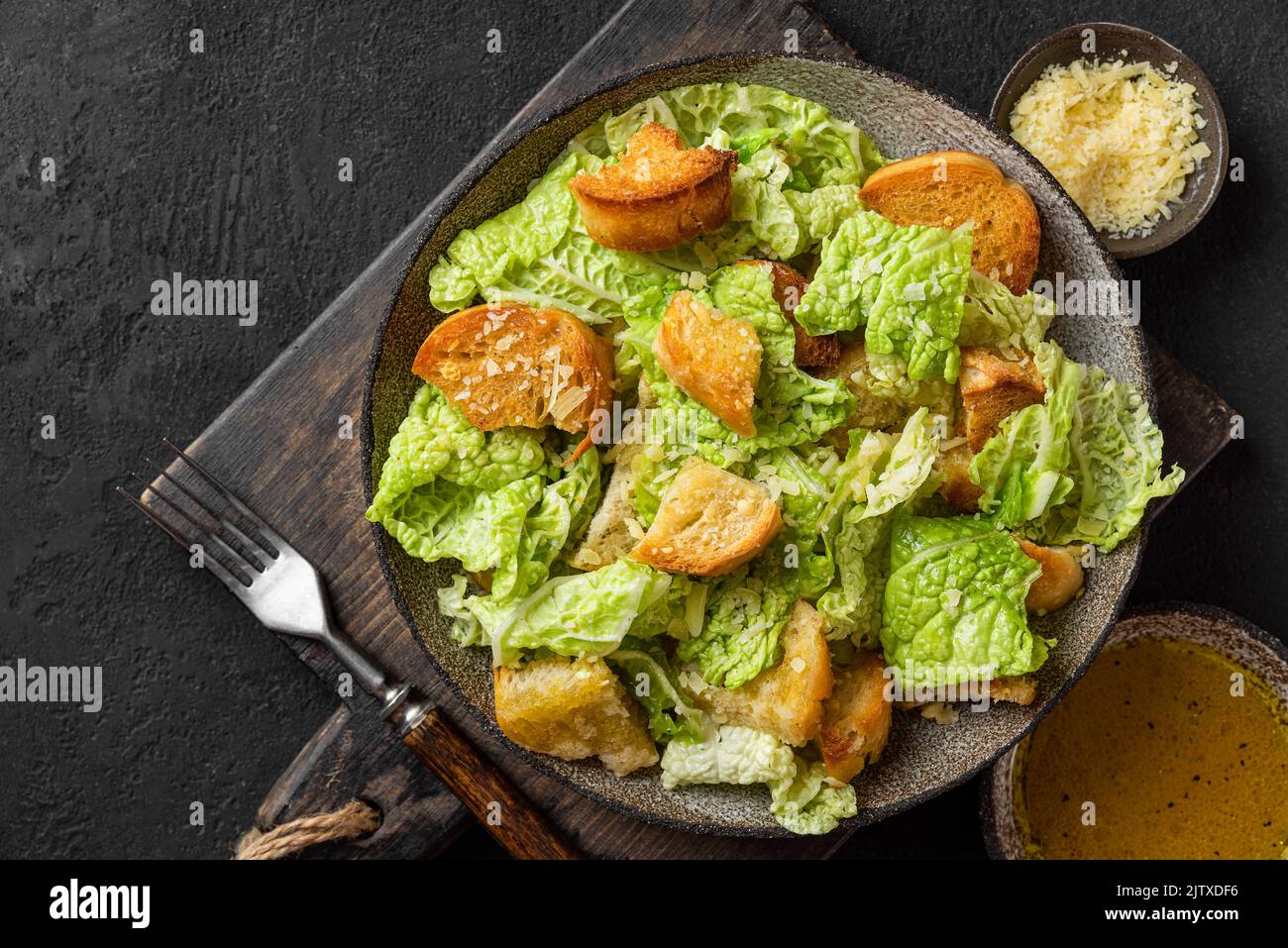 Cibo delizioso e gustoso. Insalata Caesar con parmigiano e crostini croccanti in un piatto su fondo nero. Vista dall'alto Foto Stock