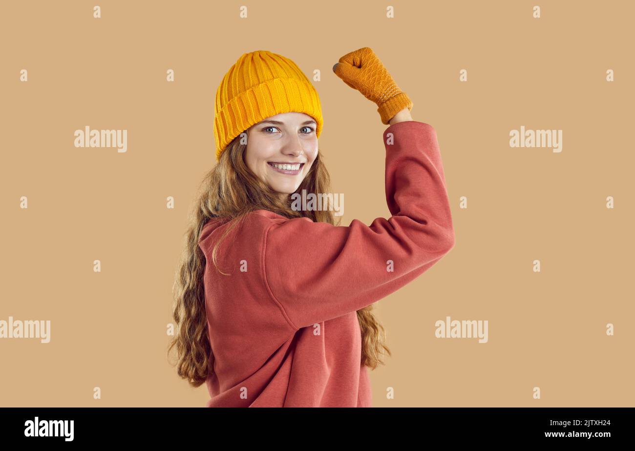 Felice sana giovane donna forte in caldi abiti autunnali flettendo il braccio e sorridendo Foto Stock