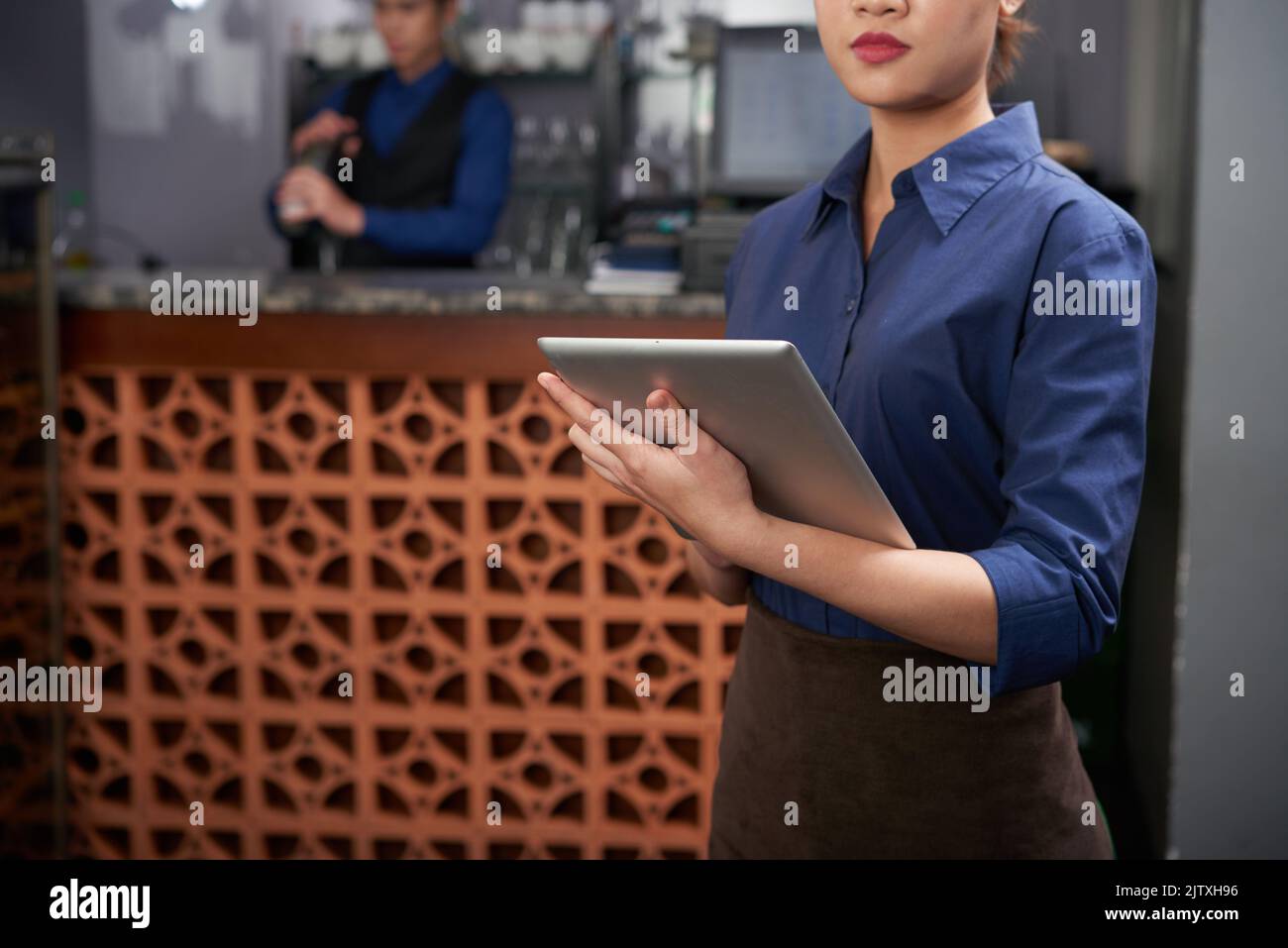 Immagine ritagliata del proprietario di bar femminile con tablet digitale Foto Stock