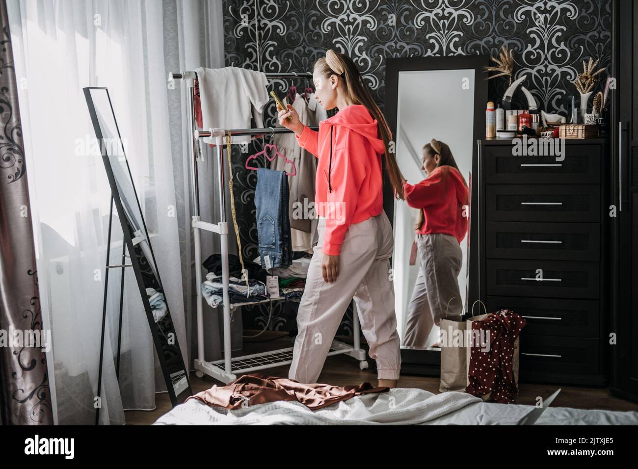 Rivendita online di spedizione e negozio Thrift. Acquistare e vendere vestiti di seconda mano. Giovane donna discluttering armadio Foto Stock