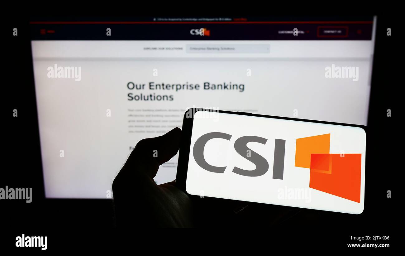 Persona che tiene il cellulare con il logo della società di tecnologia statunitense computer Services Inc. (CSI) sullo schermo di fronte alla pagina Web. Messa a fuoco sul display del telefono. Foto Stock