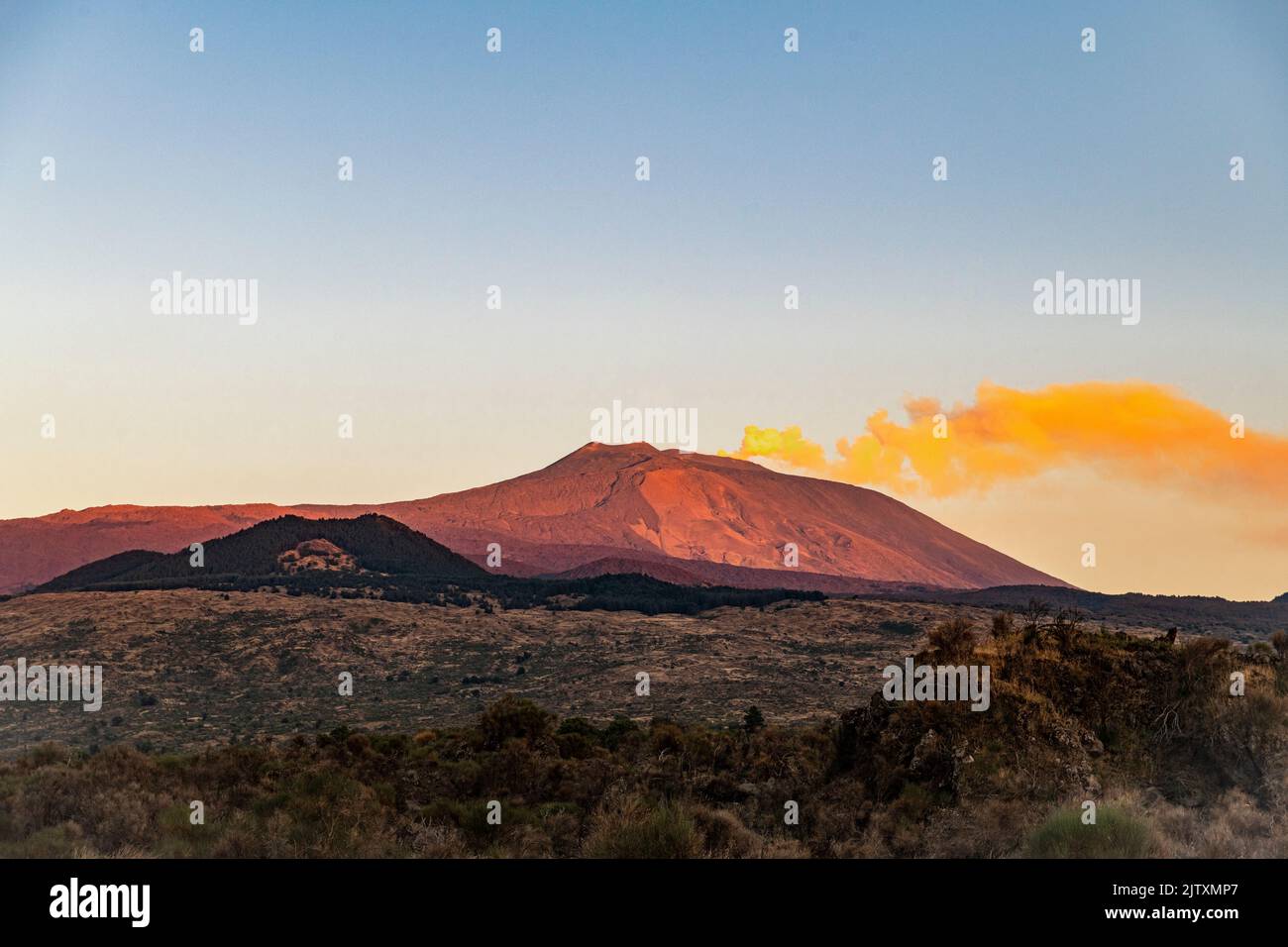 Un lungo pennacchio di sentieri di fumo dalla cima dell'Etna, illuminato dal sole tramontato, visto dal lato occidentale (Sicilia, Italia) Foto Stock