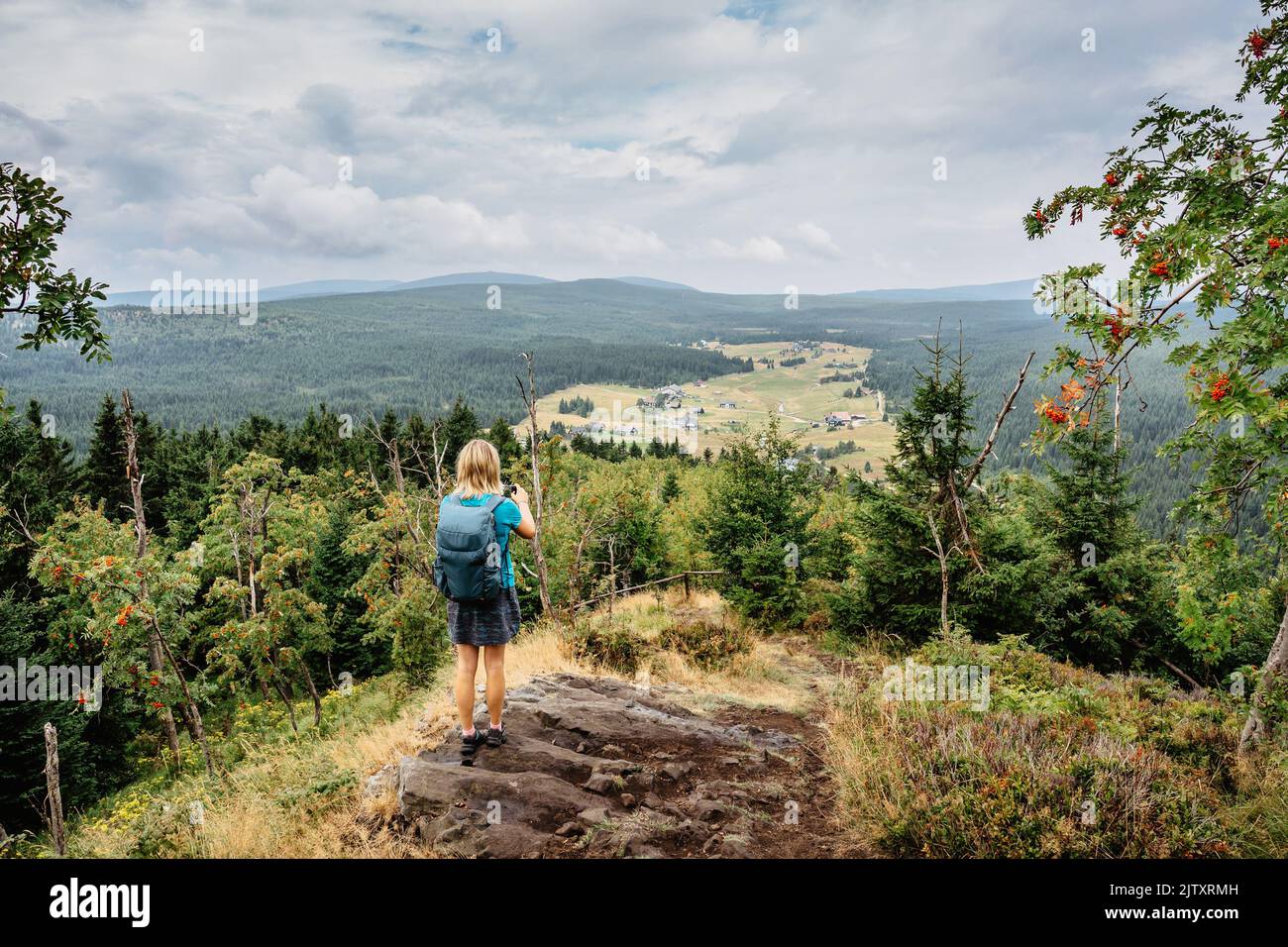 Il viaggiatore femminile usa lo smartphone per scattare foto del villaggio di Jizerka, Bukovec, Repubblica Ceca.concetto di viaggio e tecnologia.Tourist scattare foto di Europa Foto Stock