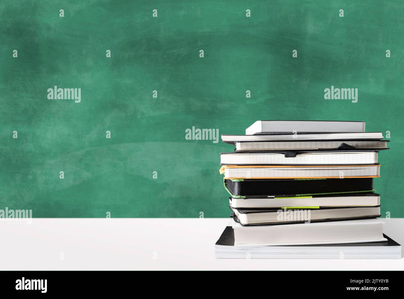 stack di libri sulla scrivania bianca contro lavagna verde con spazio copia, istruzione e concetto di scuola Foto Stock
