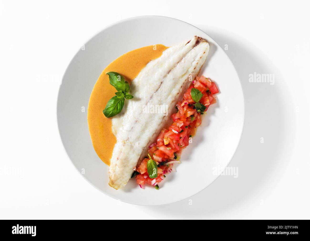Filetto di spigola alla griglia con insalata di basilico al pomodoro e sugo di carne al bianco Foto Stock