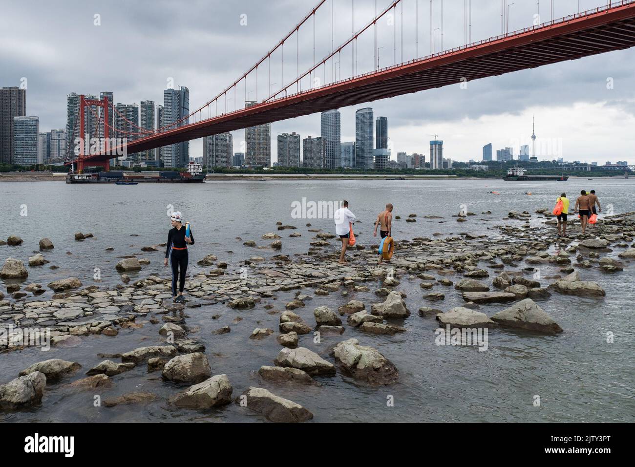 I nuotatori camminano lungo una strada rocciosa nel mezzo del fiume Yangtze a Wuhan. Per settimane, il livello dell'acqua in molte parti del fiume Yangtze era il più basso per il periodo da quando i record idrologici hanno cominciato in 1865. Nell'estate del 2022, la Cina è stata colpita dalla sua più grave ondata di caldo degli ultimi sei decenni, aggravando una siccità che ha avuto un impatto sulla produzione alimentare e industriale, sulle forniture elettriche e sui trasporti in una vasta area del paese. Il bacino del fiume Yangtze, che si estende dalla costa di Shanghai alla provincia del Sichuan, a sud-ovest della Cina, e comprende il fiume più lungo dell'Asia, è stato considerato l'area più colpita, Foto Stock