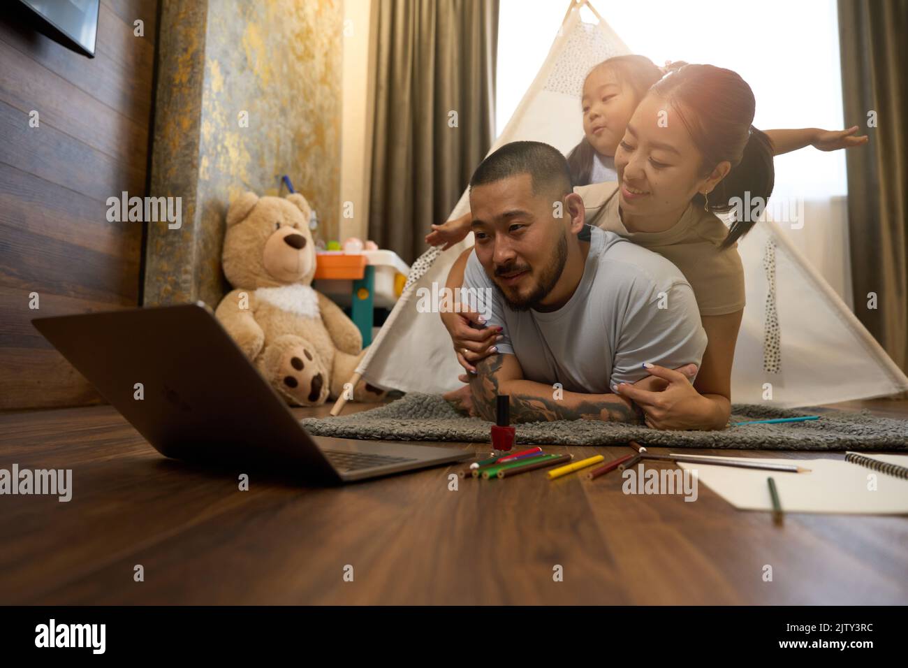 Famiglia asiatica nella camera per bambini di fronte al computer portatile Foto Stock