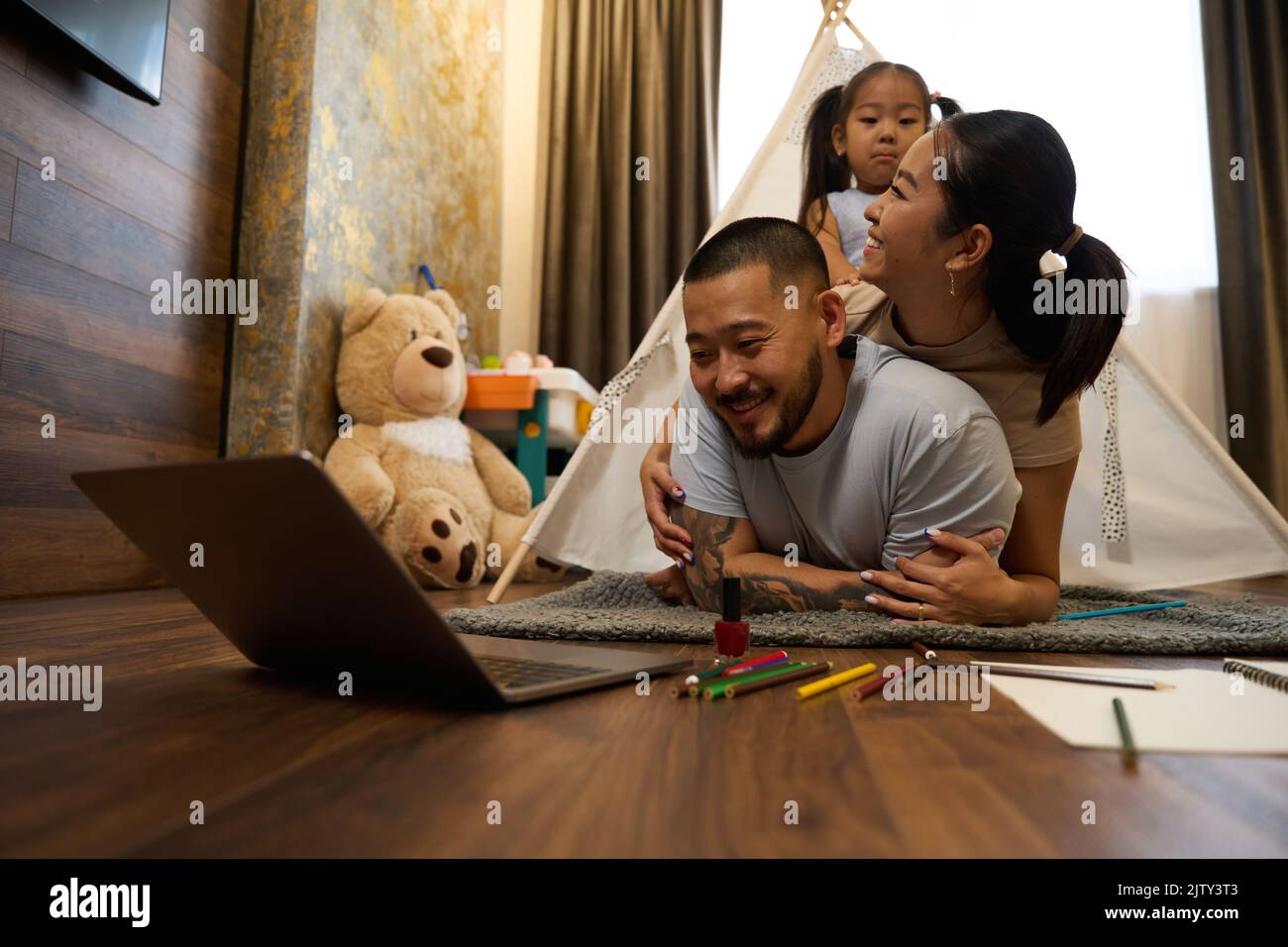 I genitori asiatici e la figlia piccola si trovano sul pavimento nella stanza dei bambini Foto Stock