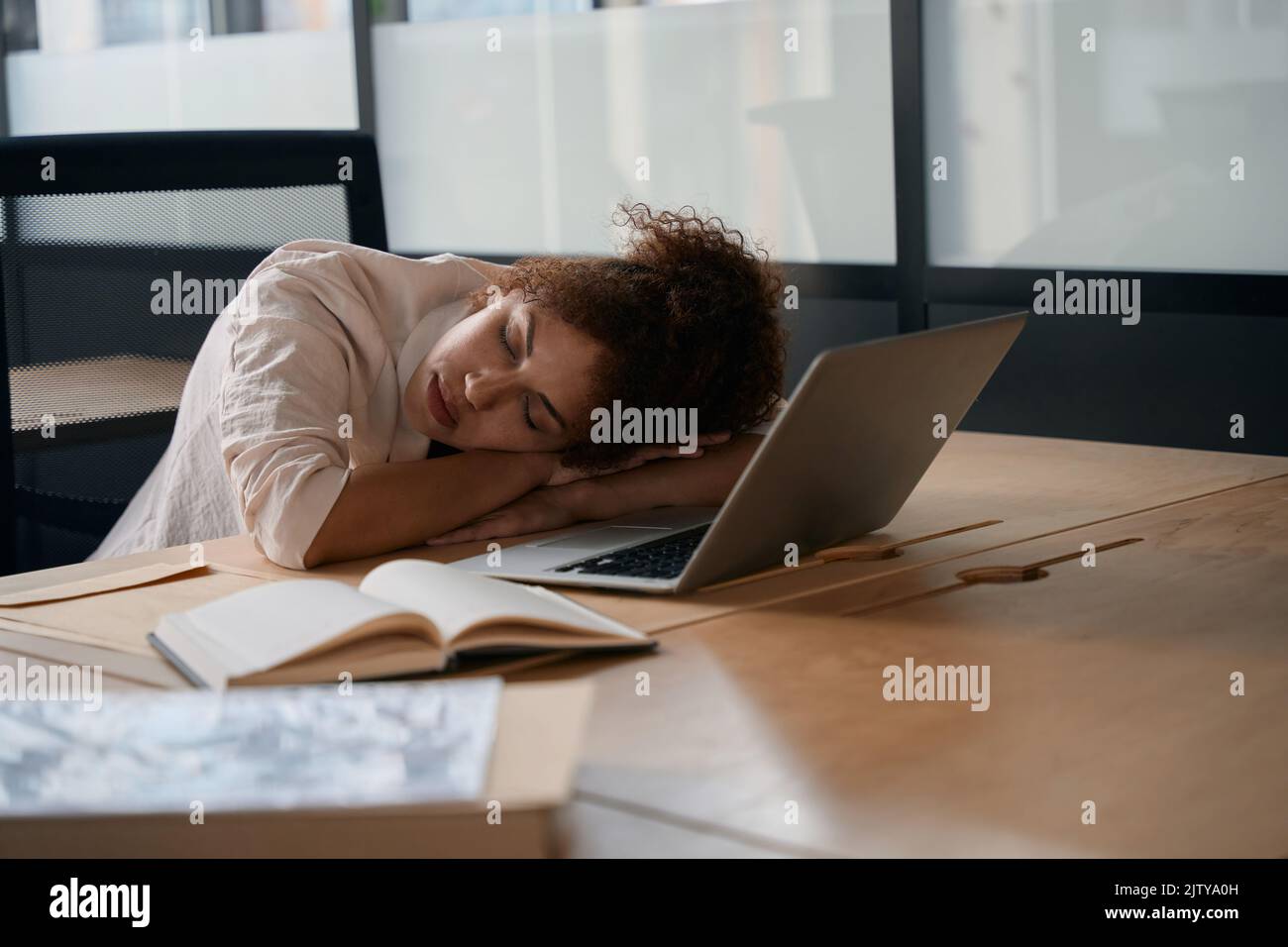 Donna addormentata con la testa appoggiata sulla scrivania Foto Stock