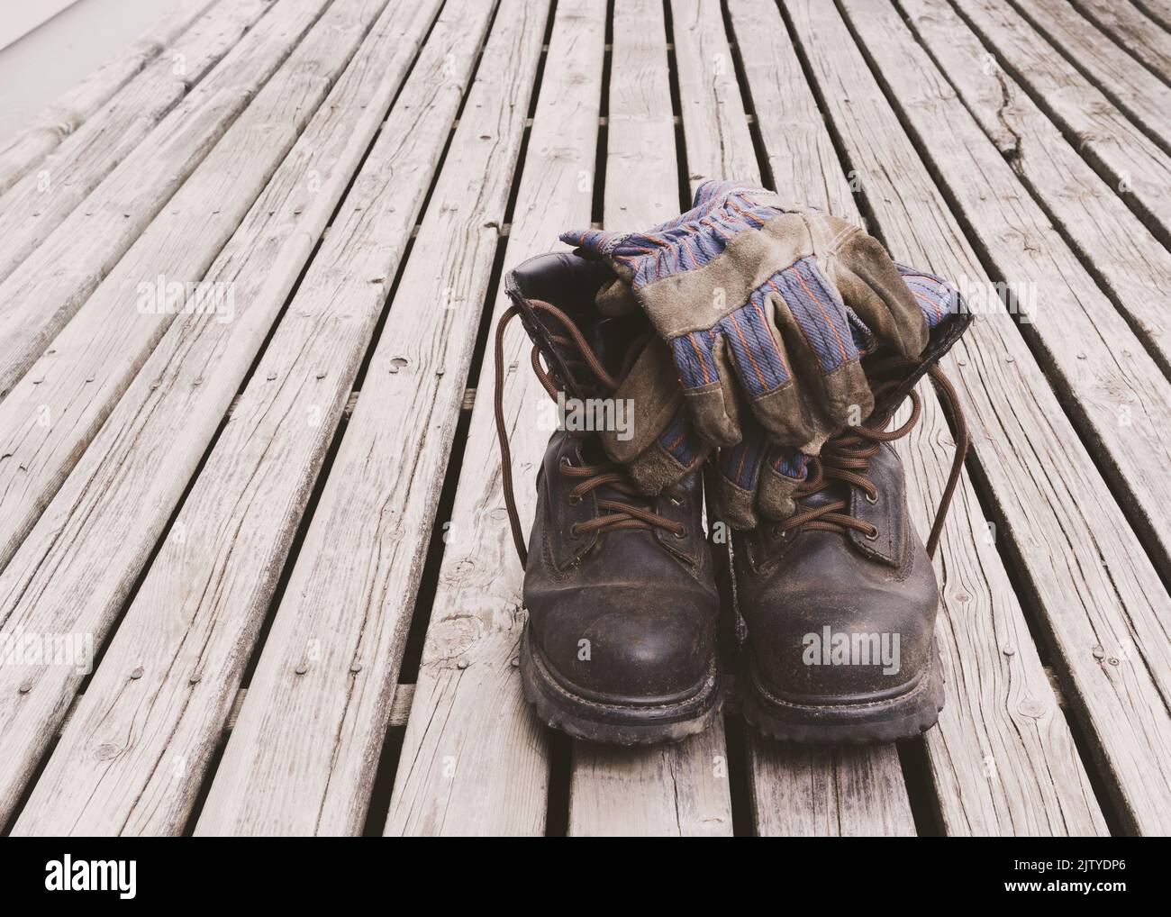 Stivali da lavoro e guanti su tavole da ponte intemperie Foto Stock