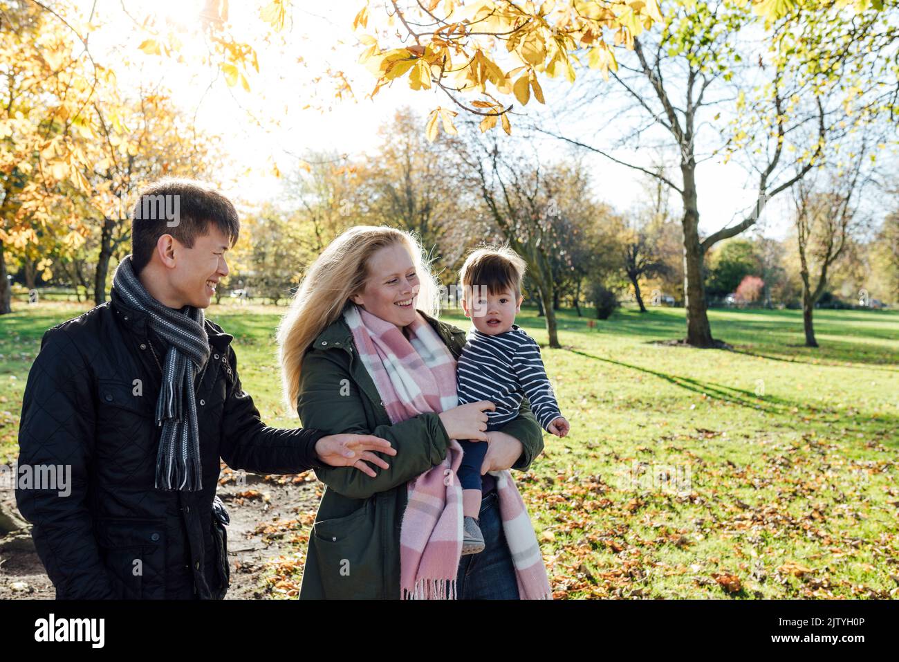 Una famiglia che si gode una giornata in un parco pubblico insieme a Northumberland, Inghilterra nord-orientale. La donna sta portando il bambino mentre l'uomo guarda Foto Stock