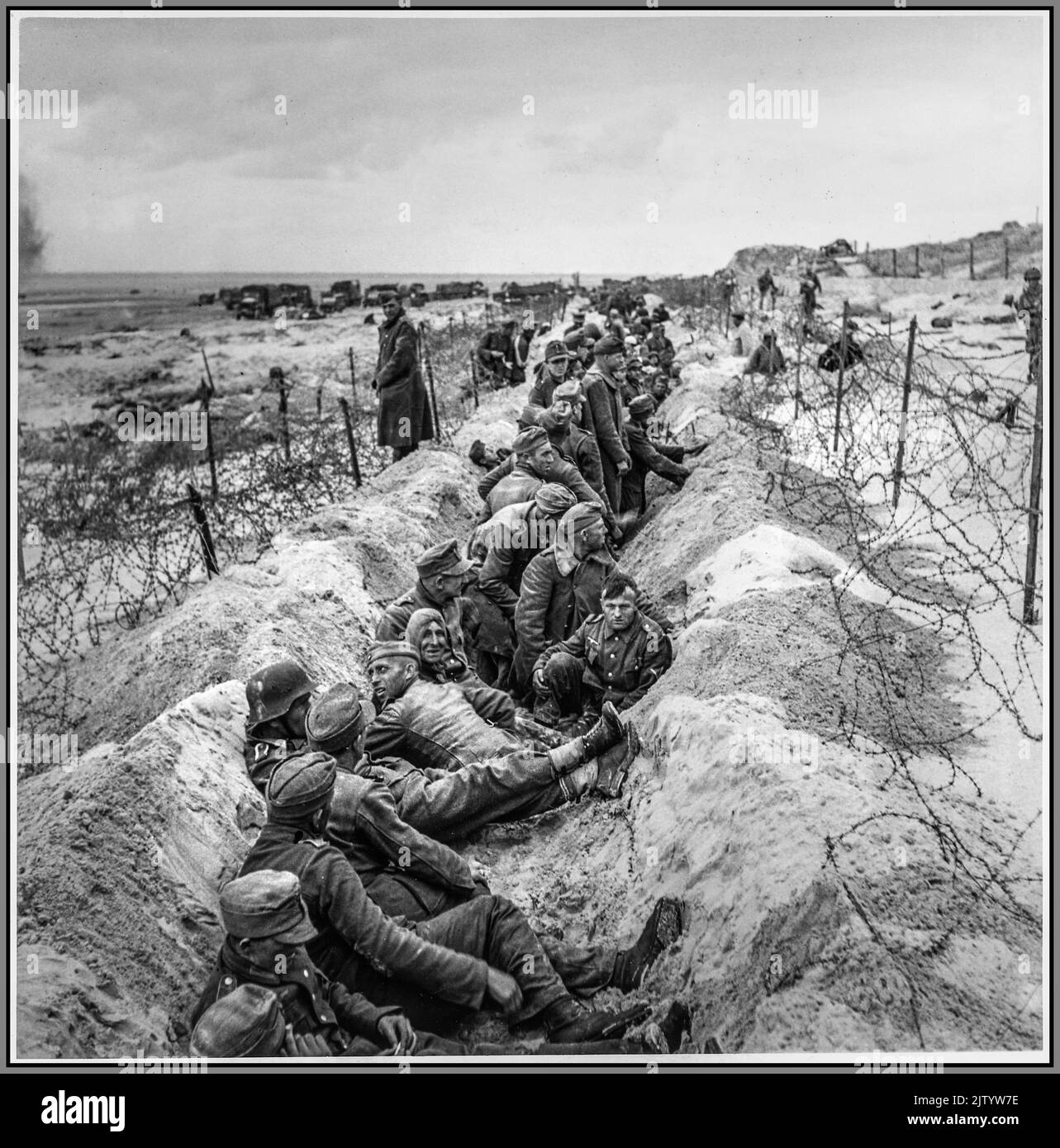 WW2 Germania nazista POWs spiagge di Normandia dopo il D-Day 1944 con i prigionieri di guerra nazisti tedeschi dopo il D-Day con soldati americani che li sorvegliano prima del trasporto seconda guerra mondiale seconda guerra mondiale Francia settentrionale Foto Stock