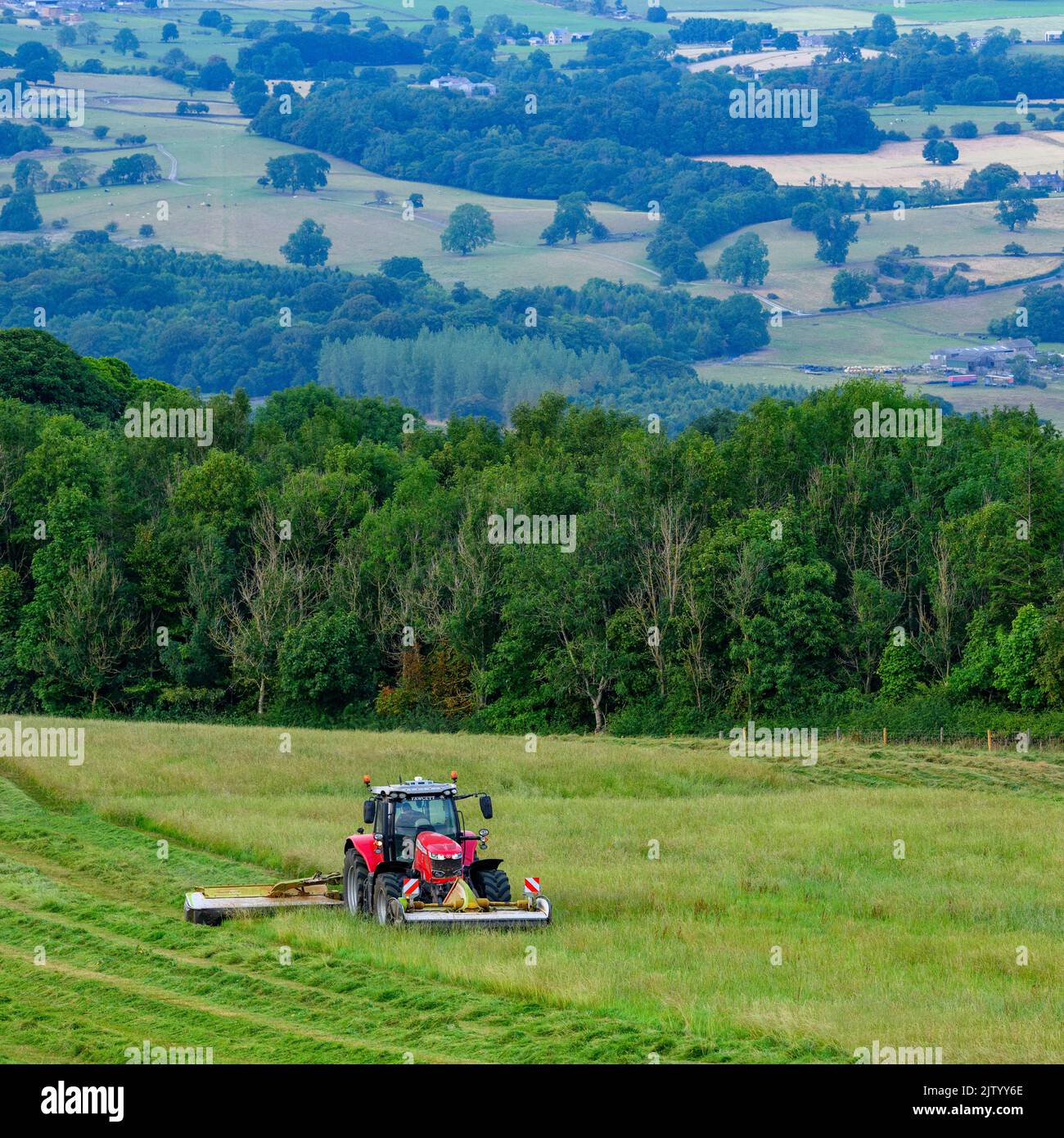 Trattore rosso Massey Ferguson 7719 S e disco Claas 3200c fieno da fieno - terreno agricolo collinare, campagna panoramica Wharfedale, Yorkshire, Inghilterra, Regno Unito. Foto Stock