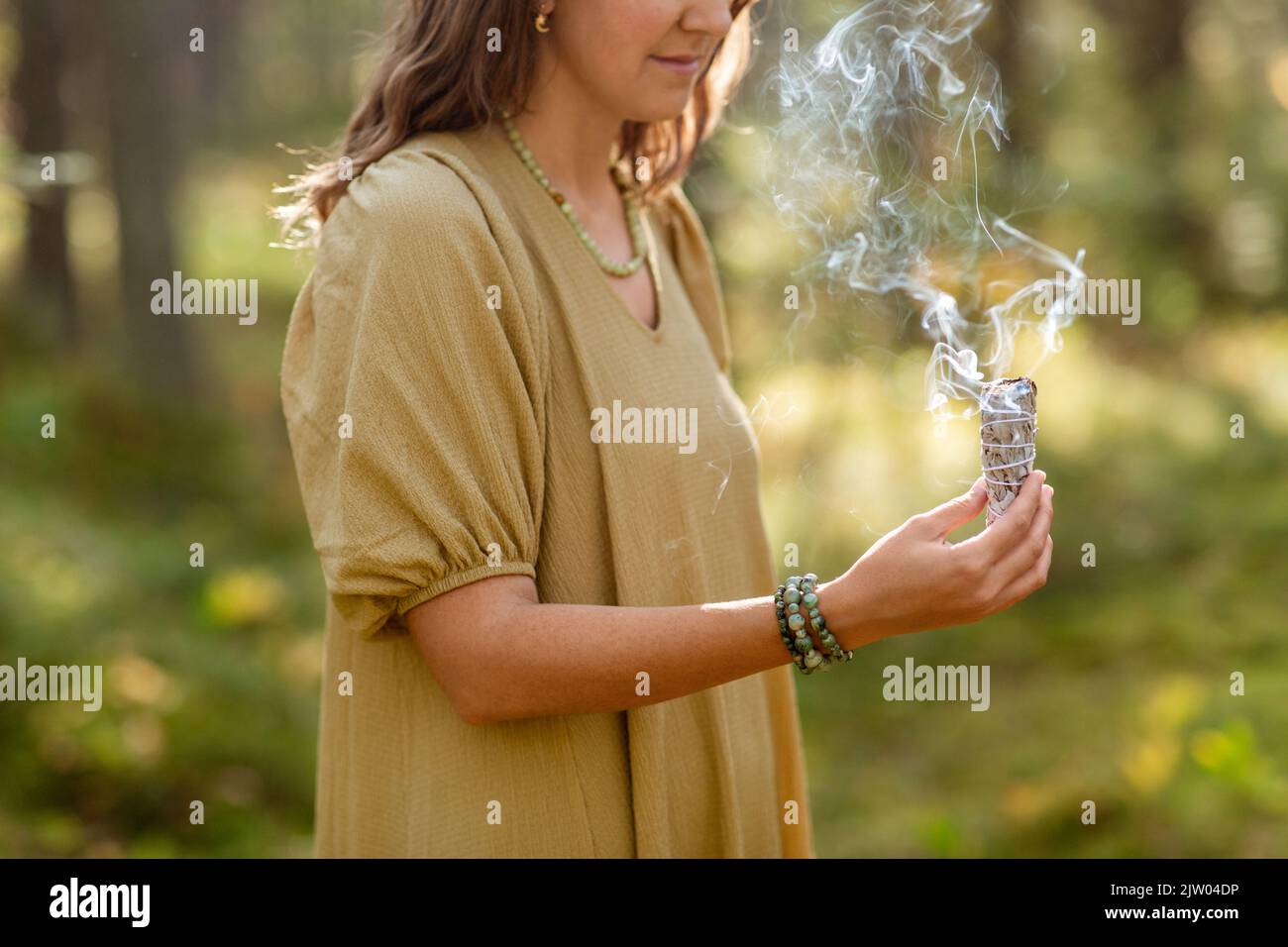 donna con salvia che esegue rituale magico nella foresta Foto Stock