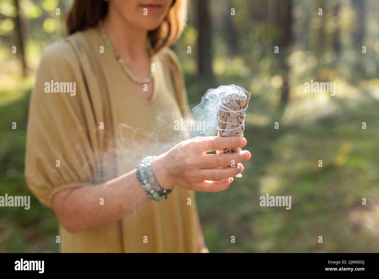 donna con salvia che esegue rituale magico nella foresta Foto Stock