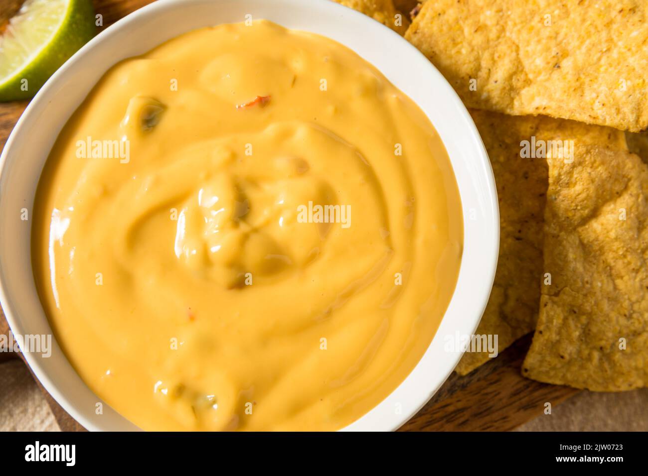 Salsa di formaggio Queso giallo fatta in casa con patatine di tortilla e lime Foto Stock