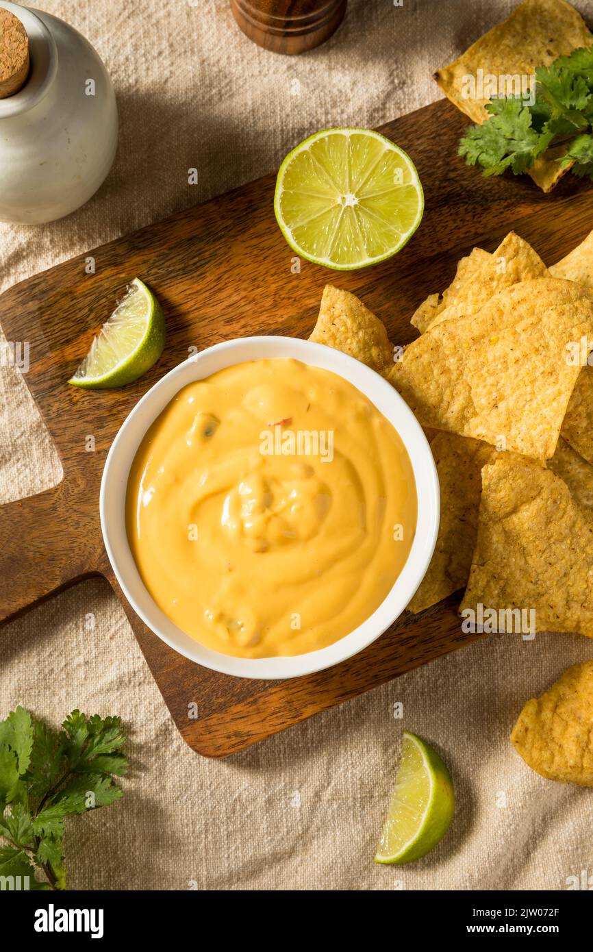 Salsa di formaggio Queso giallo fatta in casa con patatine di tortilla e lime Foto Stock