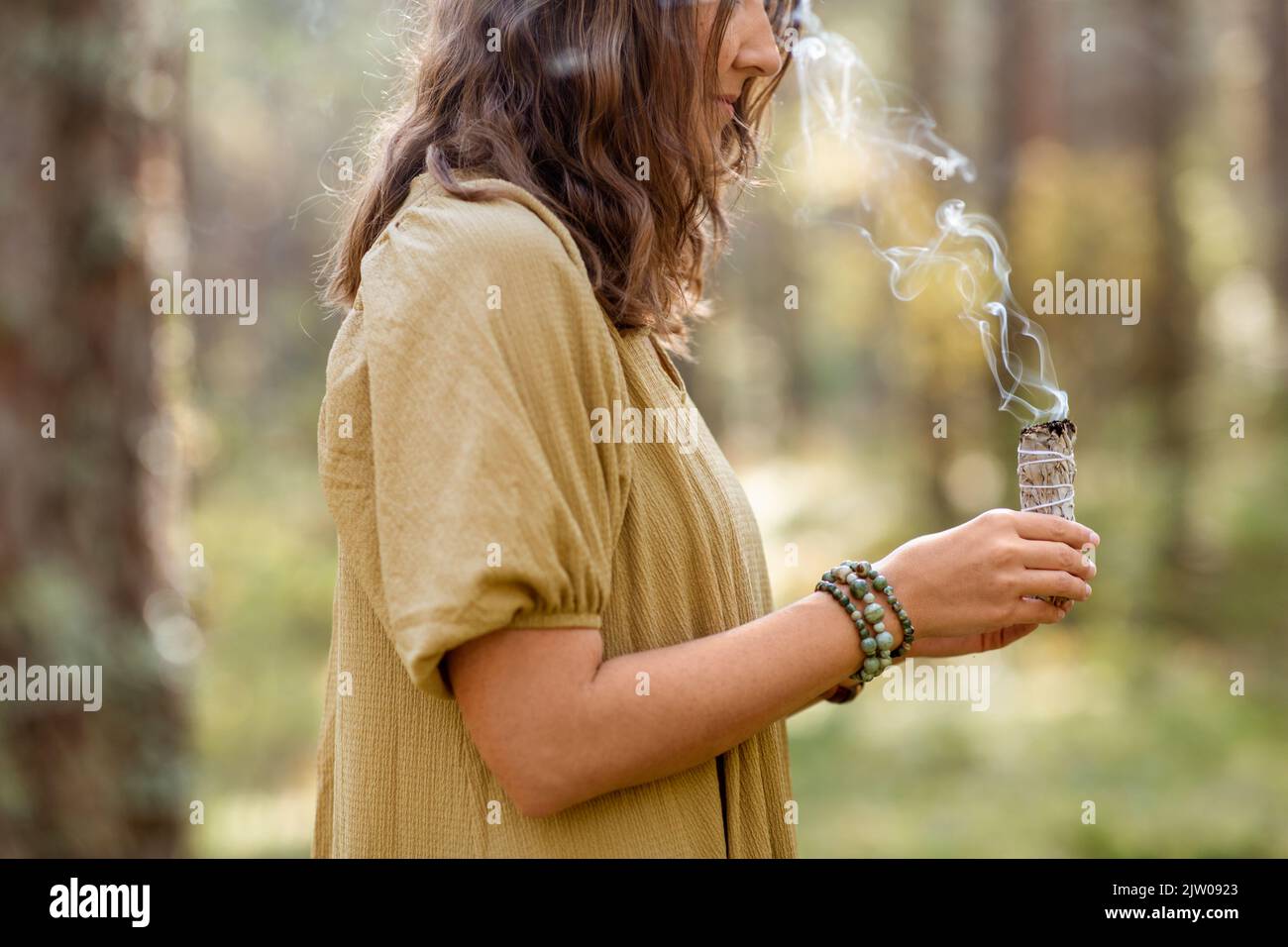 donna con salvia che esegue rituale magico nella foresta Foto Stock