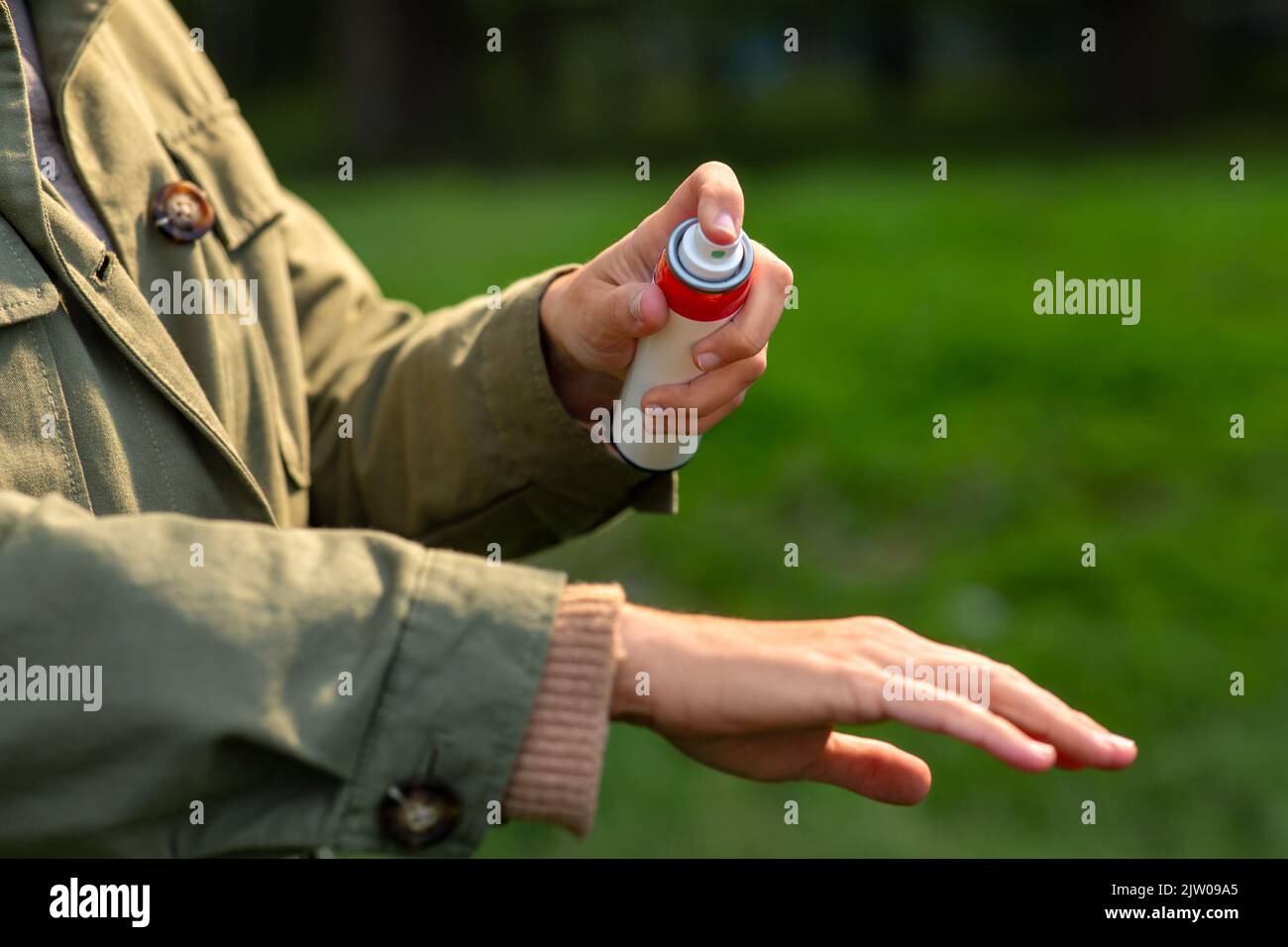 donna spruzzando repellente per insetti a portata di mano al parco Foto Stock