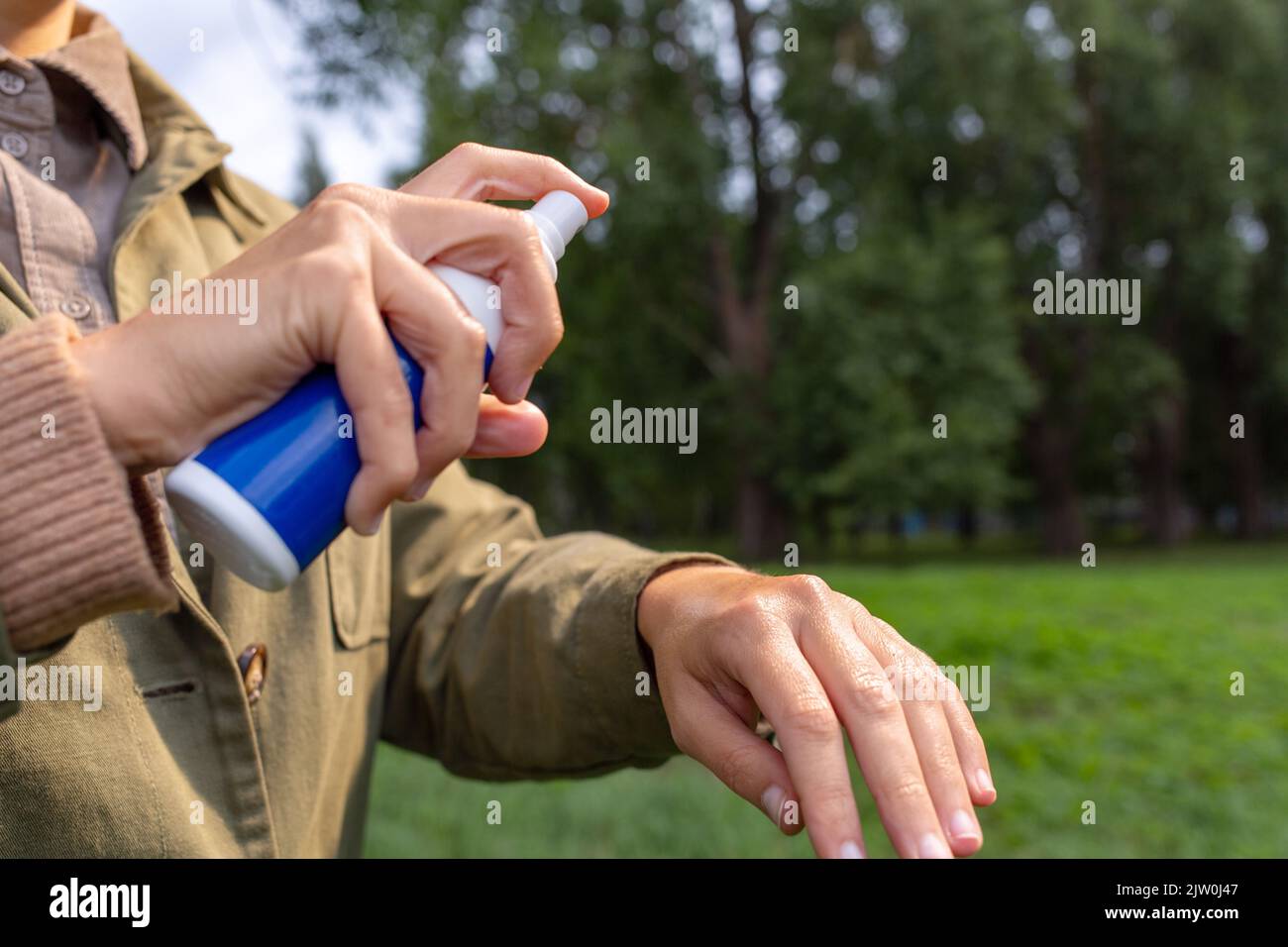 donna spruzzando repellente per insetti a portata di mano al parco Foto Stock